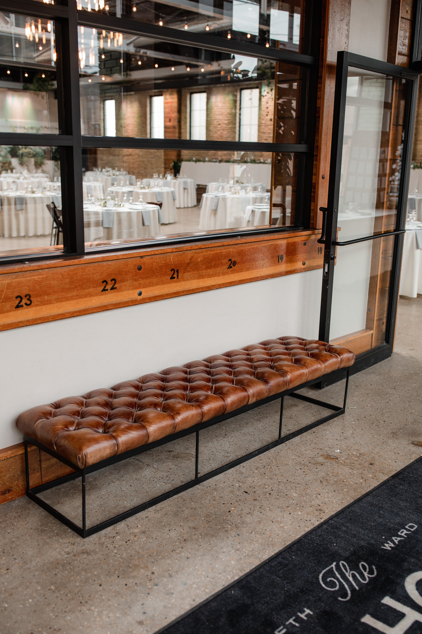 Inside the front doors of the ivy house is a leather seating bench and recycled wood window frames