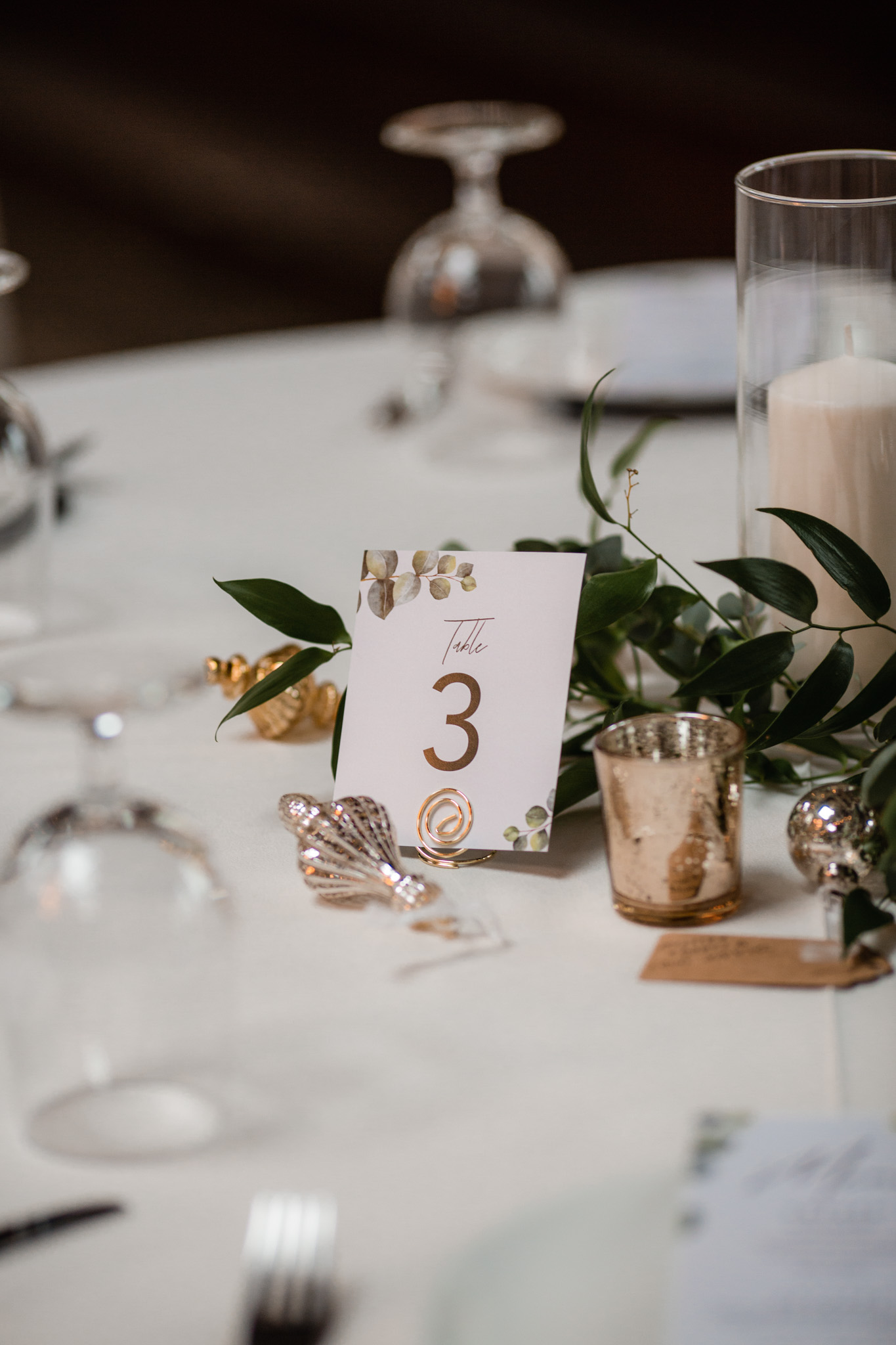 Wedding table decorations with greenery, candles, and Christmas ornament favors