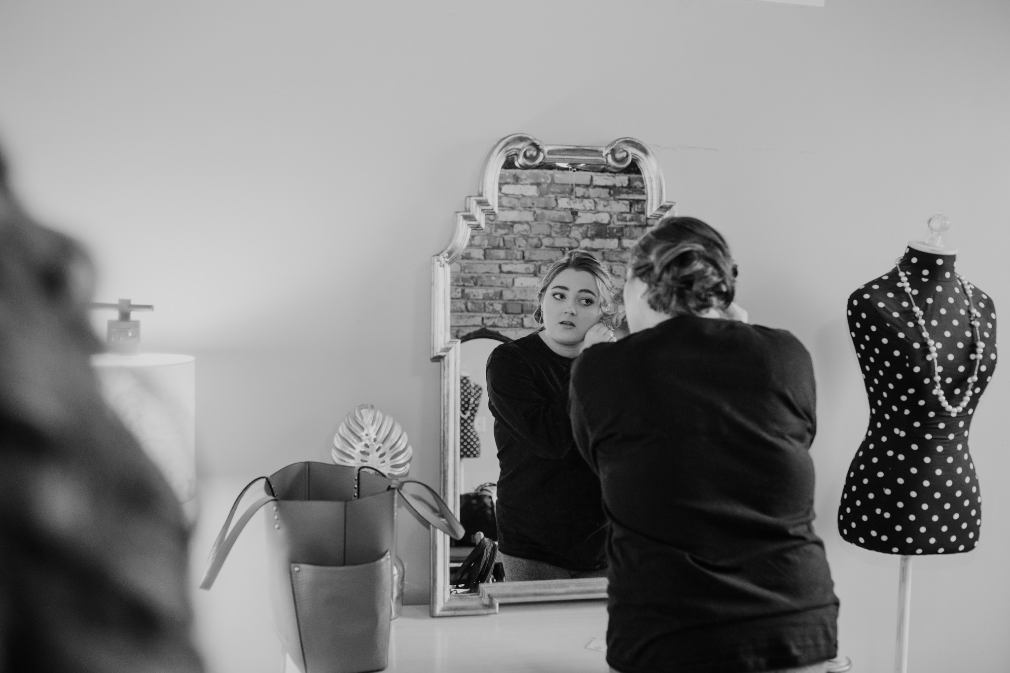 Bridesmaid putting on jewelry in a mirror - milwaukee wedding photographer - creative compositions - good lighting - natural colors editing