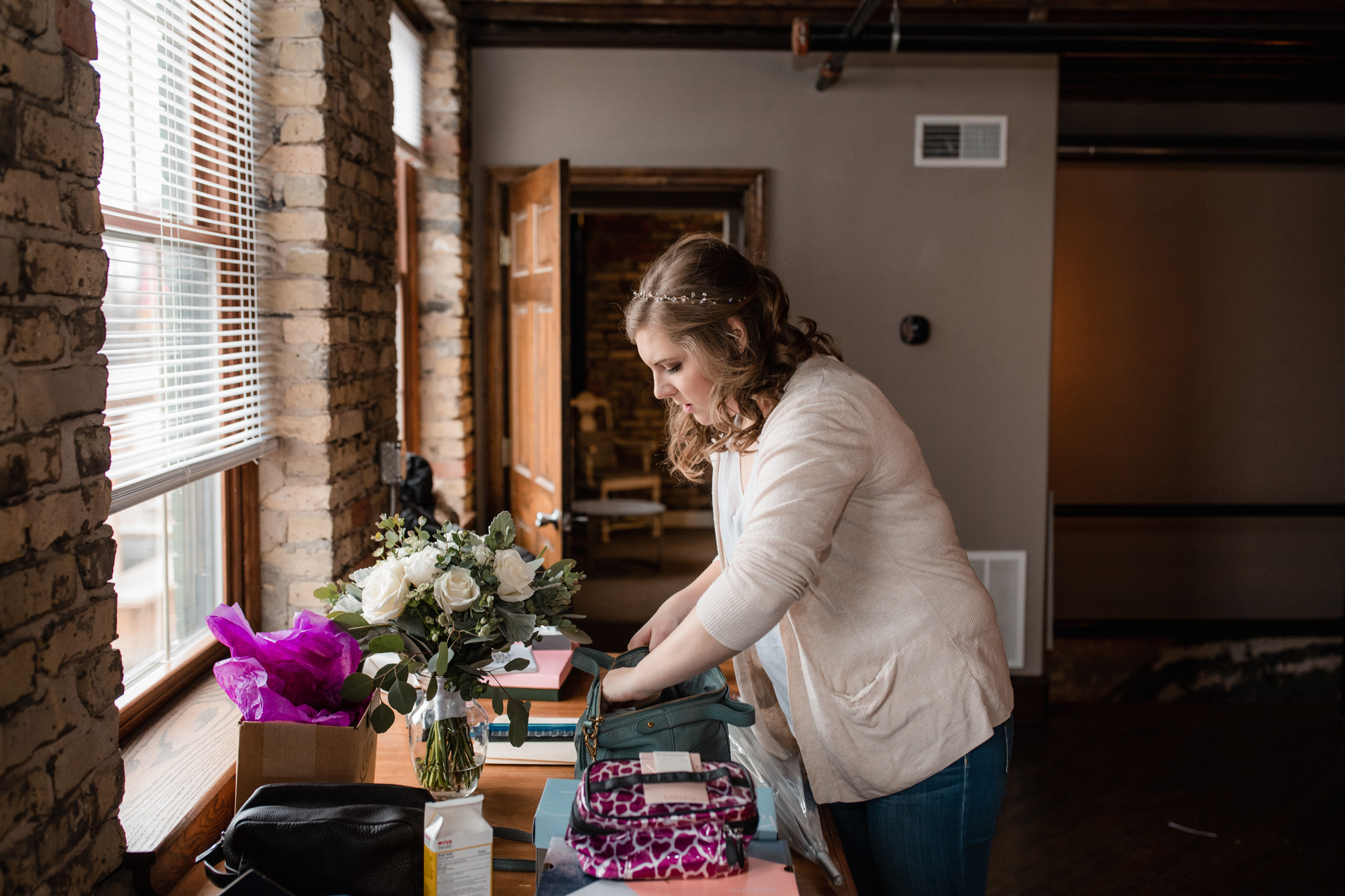 Bride with headband standing next to her bouquet looking for makeup