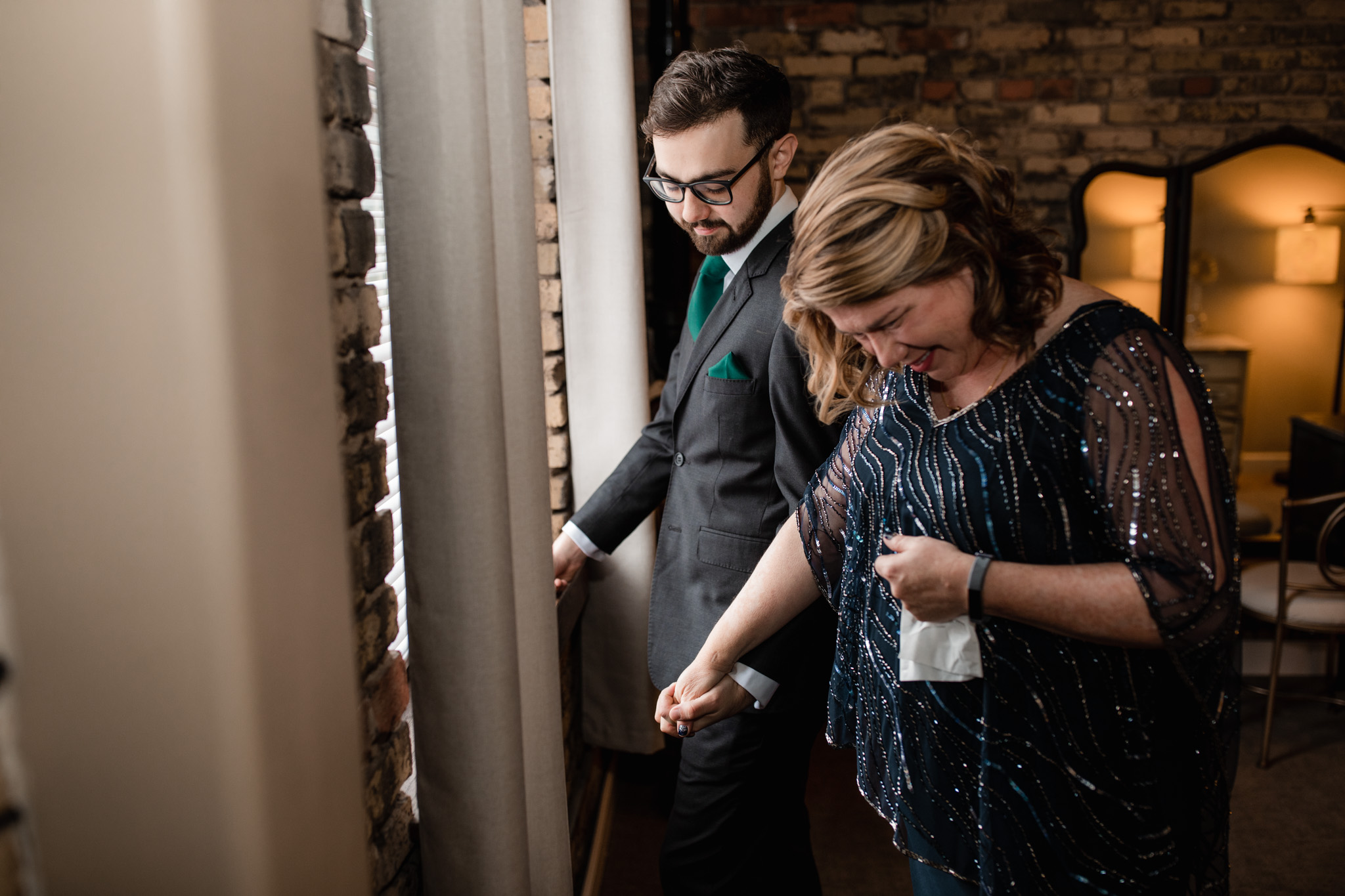 Mother of the groom holding groom's hand before his wedding - emotional candid wedding photography in Milwaukee Wisconsin