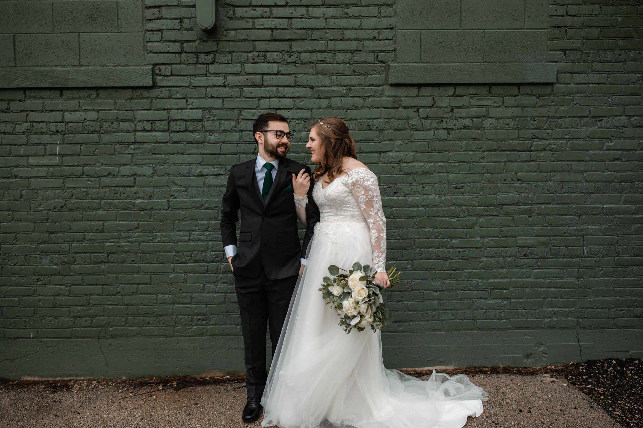 Couple's wedding portraits Ivy House green brick wall - white flowers
