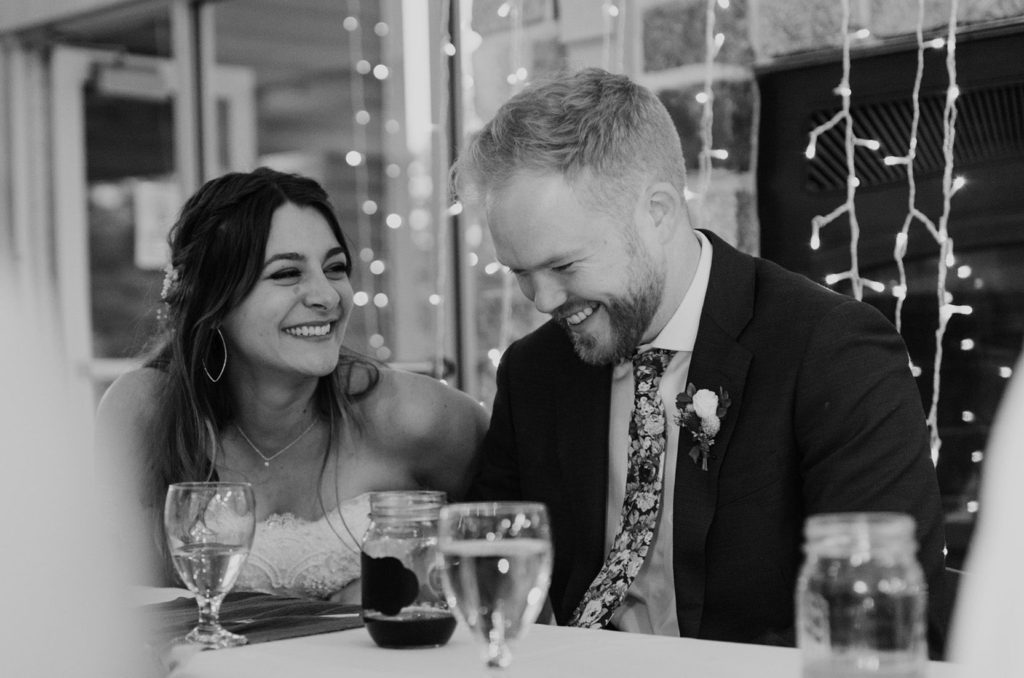 A couple sits with their guests at this wedding with a nontraditional seating arrangement