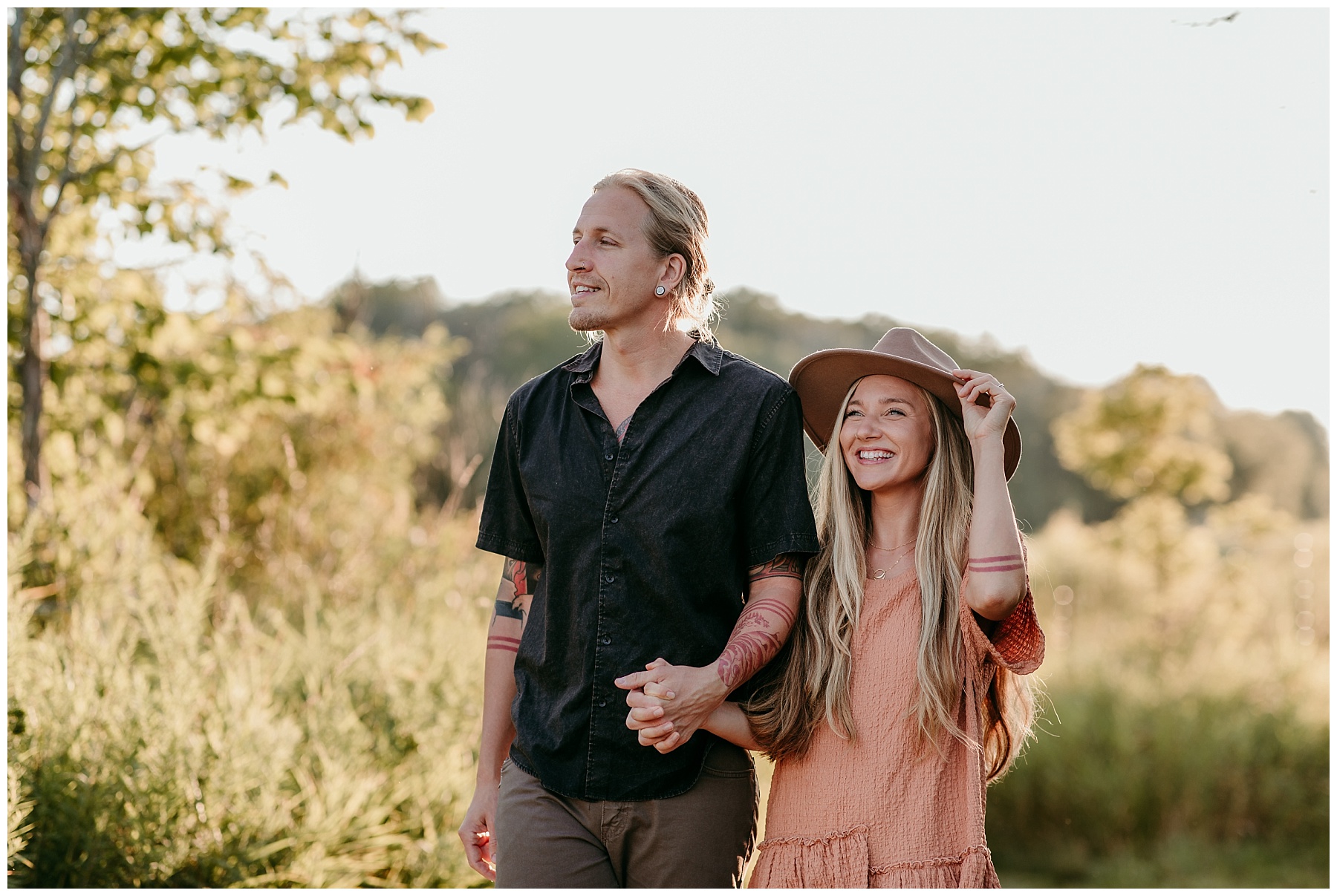 tattooed couple in a field wearing a prairie hat