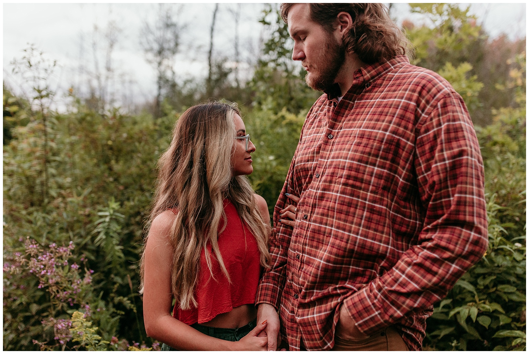 rad couple wearing orange and green for pictures in the woods