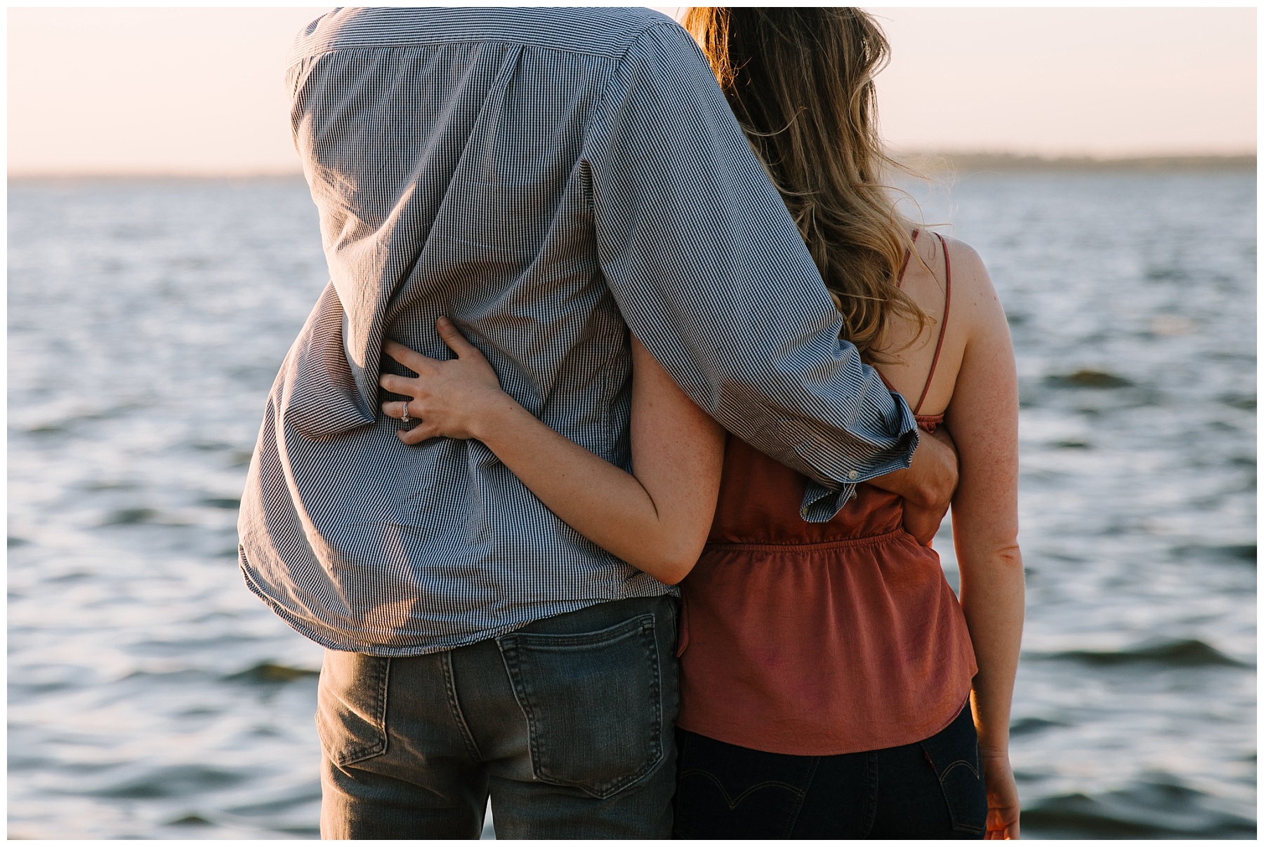 Girl and guy with their arms wrapped around each other's backs as they look over Lake Mendota in Madison Wisconsin