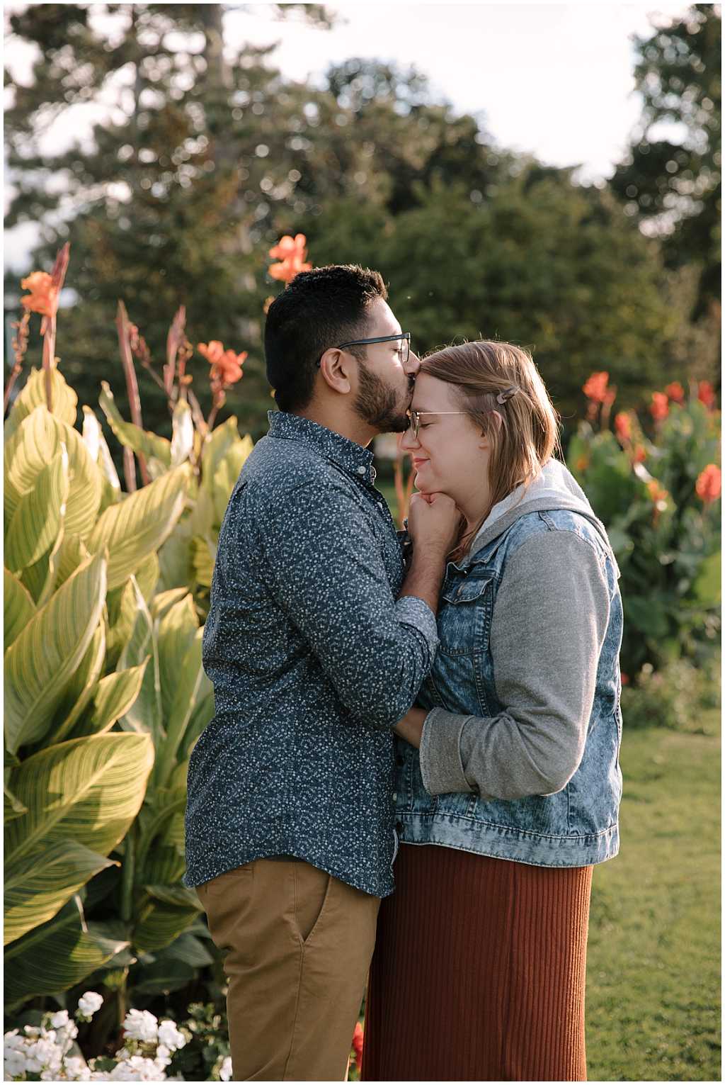 Man kissing woman on the head. Golden sunlight illuminates them from behind.