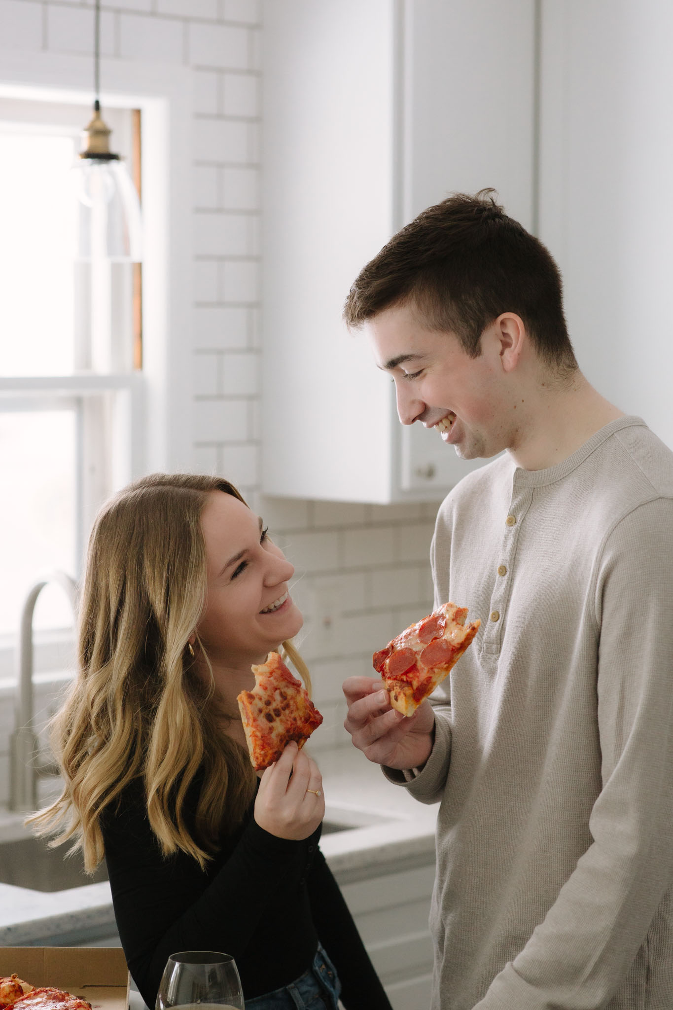 Couple eating pizza and drinking wine in kitchen