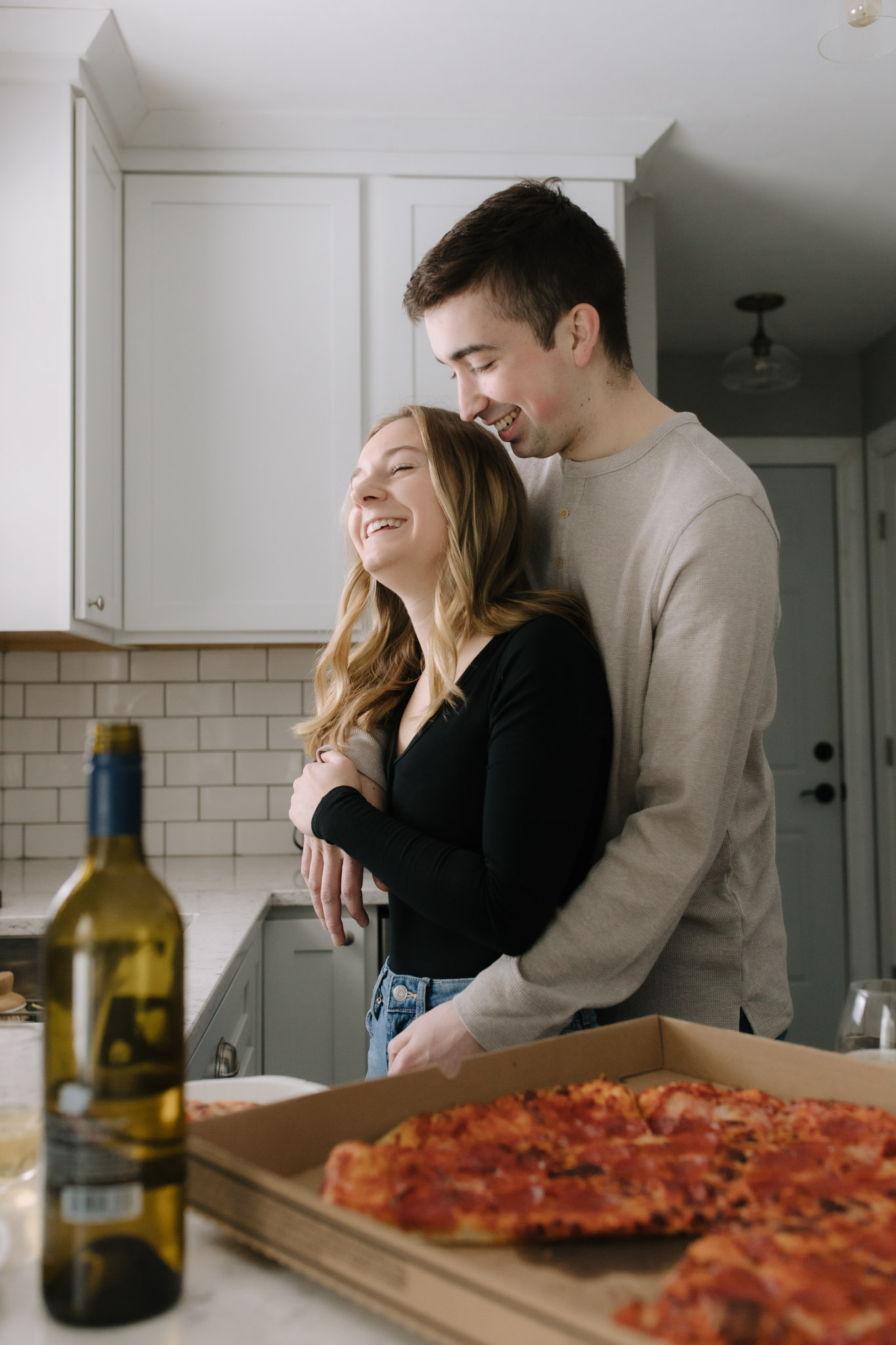 cute couple laughing and drinking wine in the kitchen of their new modern house