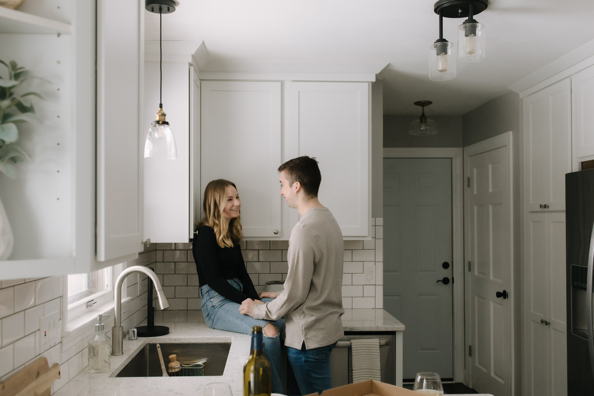 Couple sitting on kitchen counter of new modern home in port washington for new home photoshoot celebration