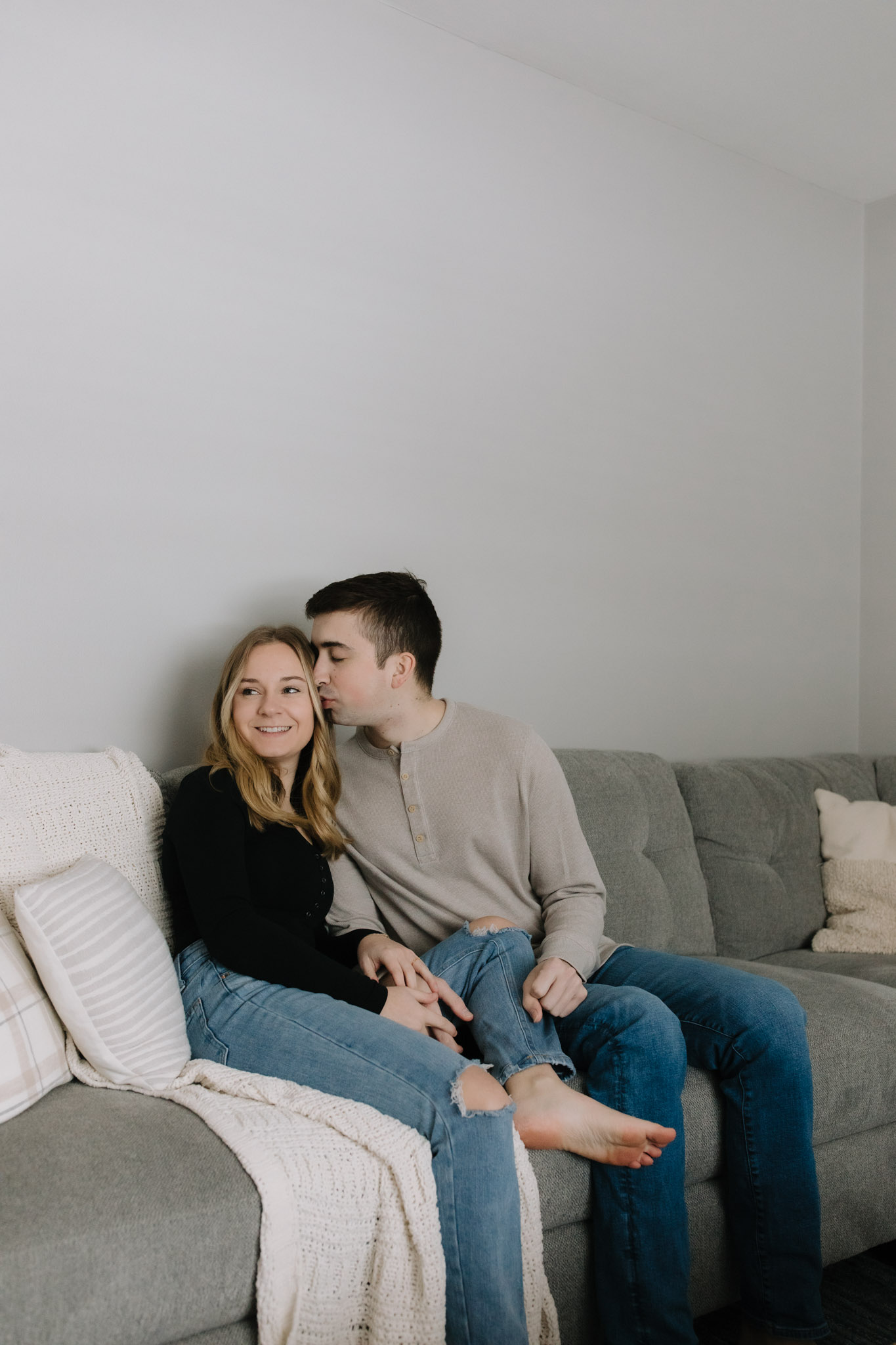 Couple sitting on a gray couch in their new Port Washington home celebrating their purchase with a new home photoshoot