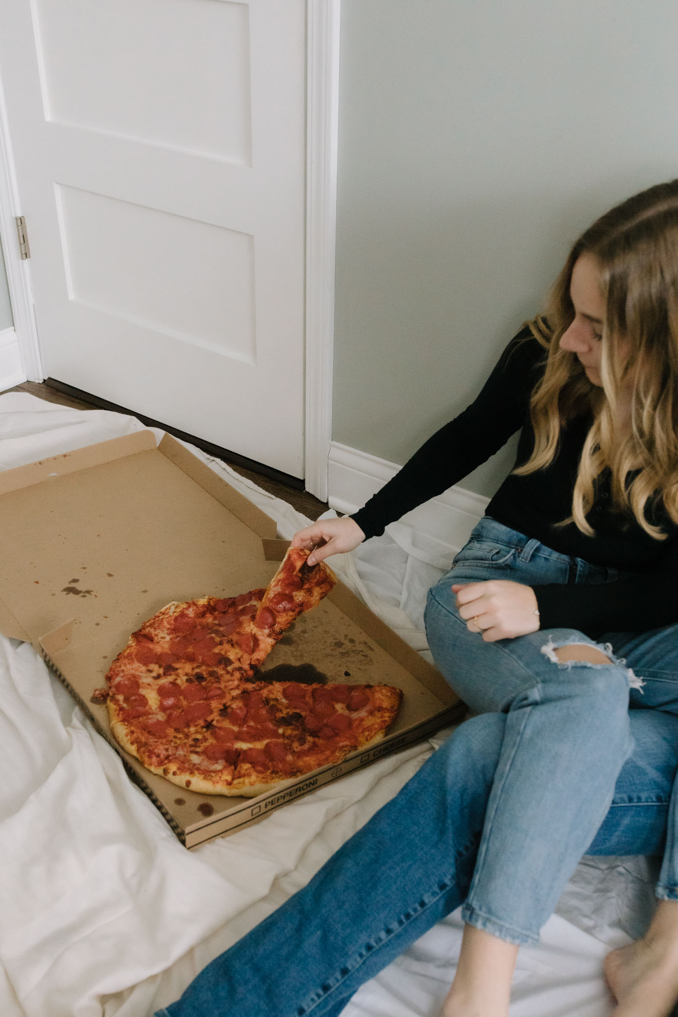 couple eating Costco pizza on the floor while painting new home photoshoot