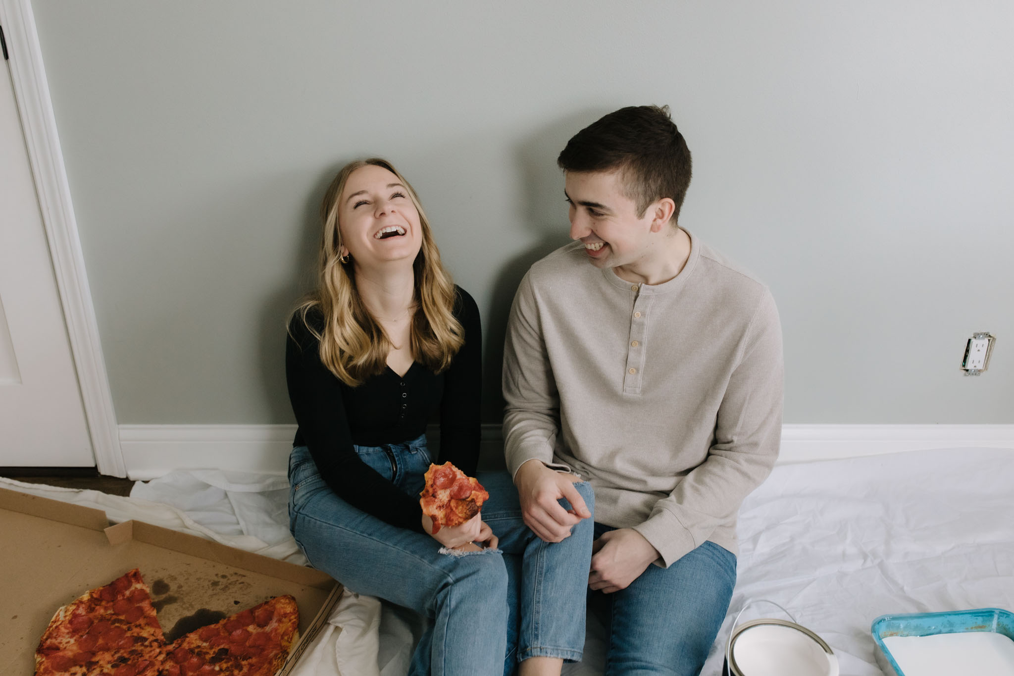 Couple eating pizza on the floor while painting their new house - New home photoshoot