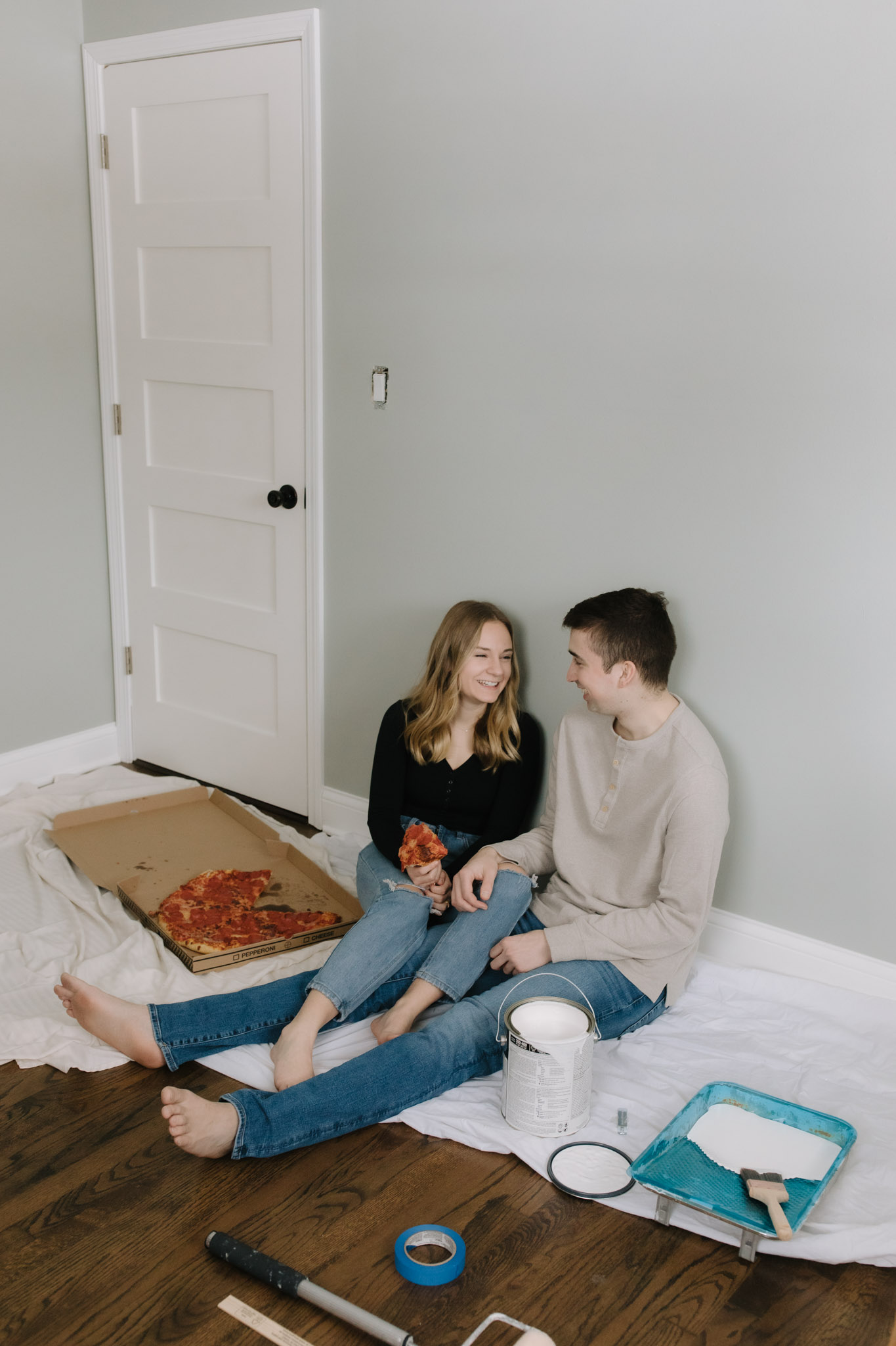 Couple eating pizza on the floor while painting their new house - New home photoshoot