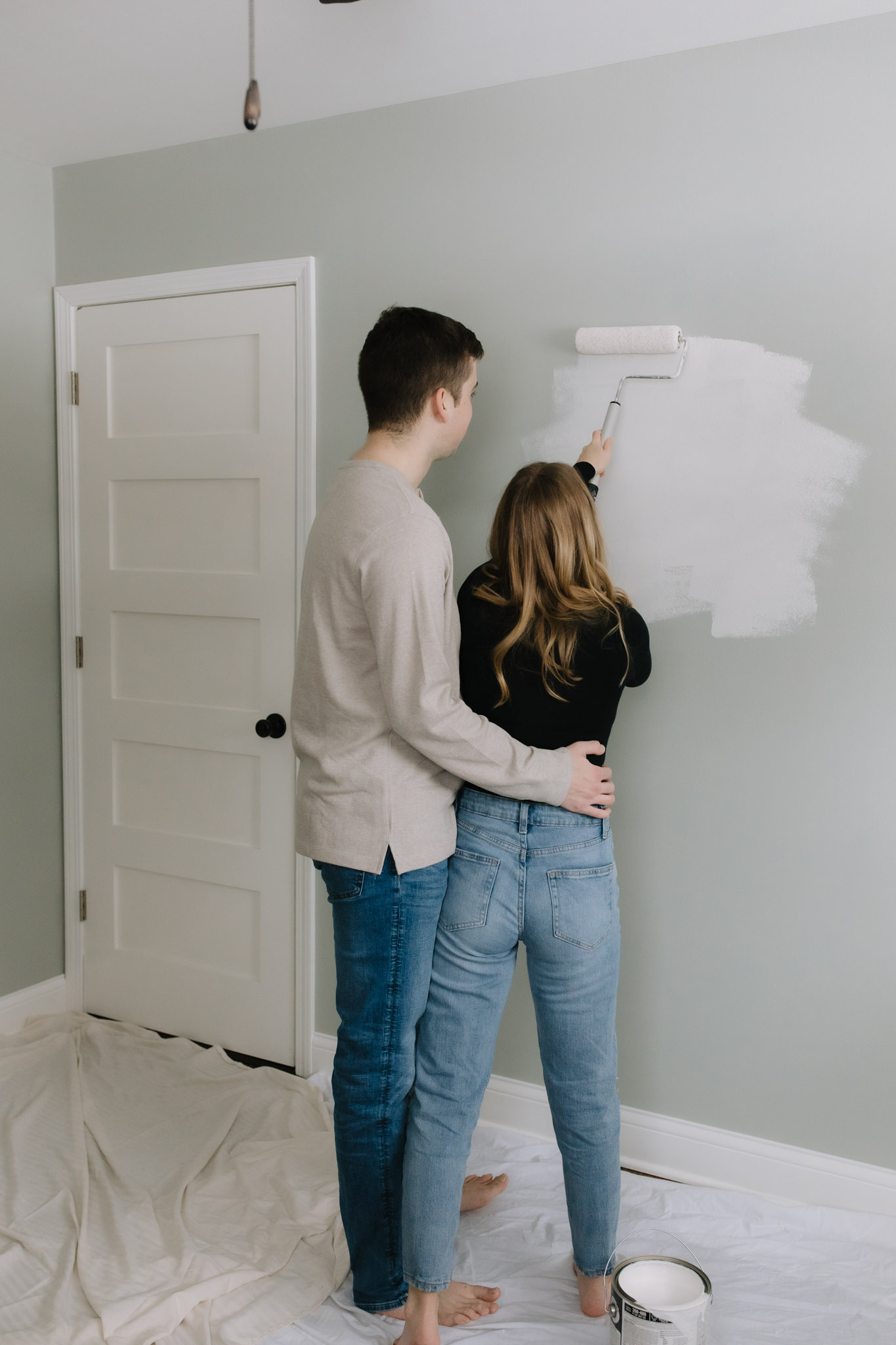 Young couple painting Port Washington home white for photoshoot
