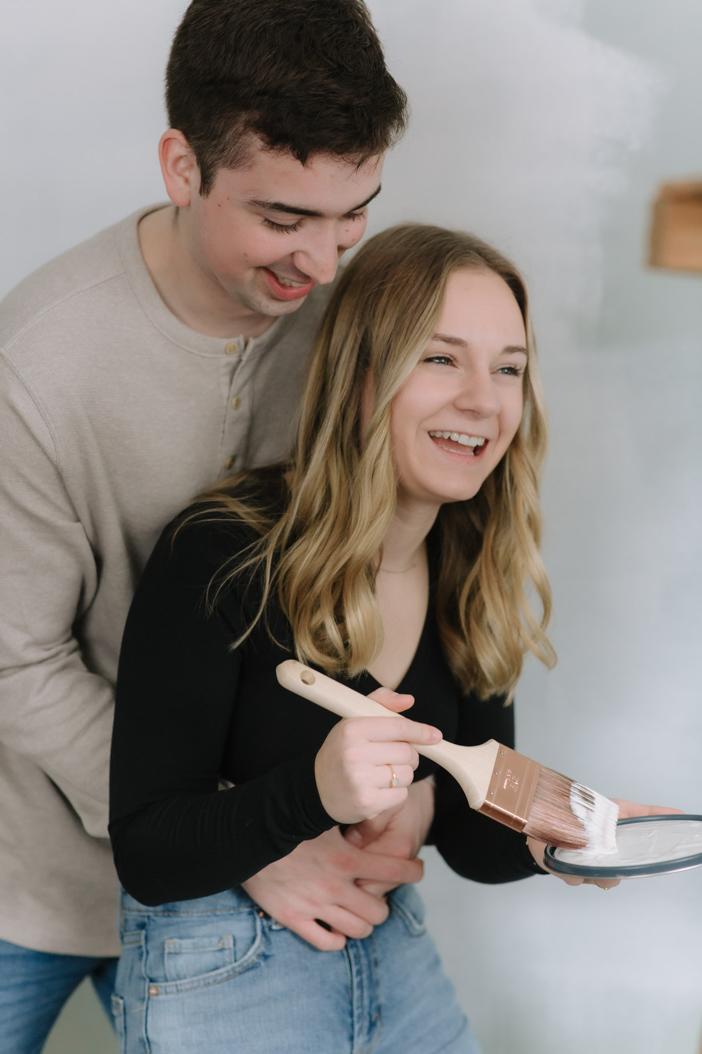 Couple laughing with paint brushes as they paint their new home