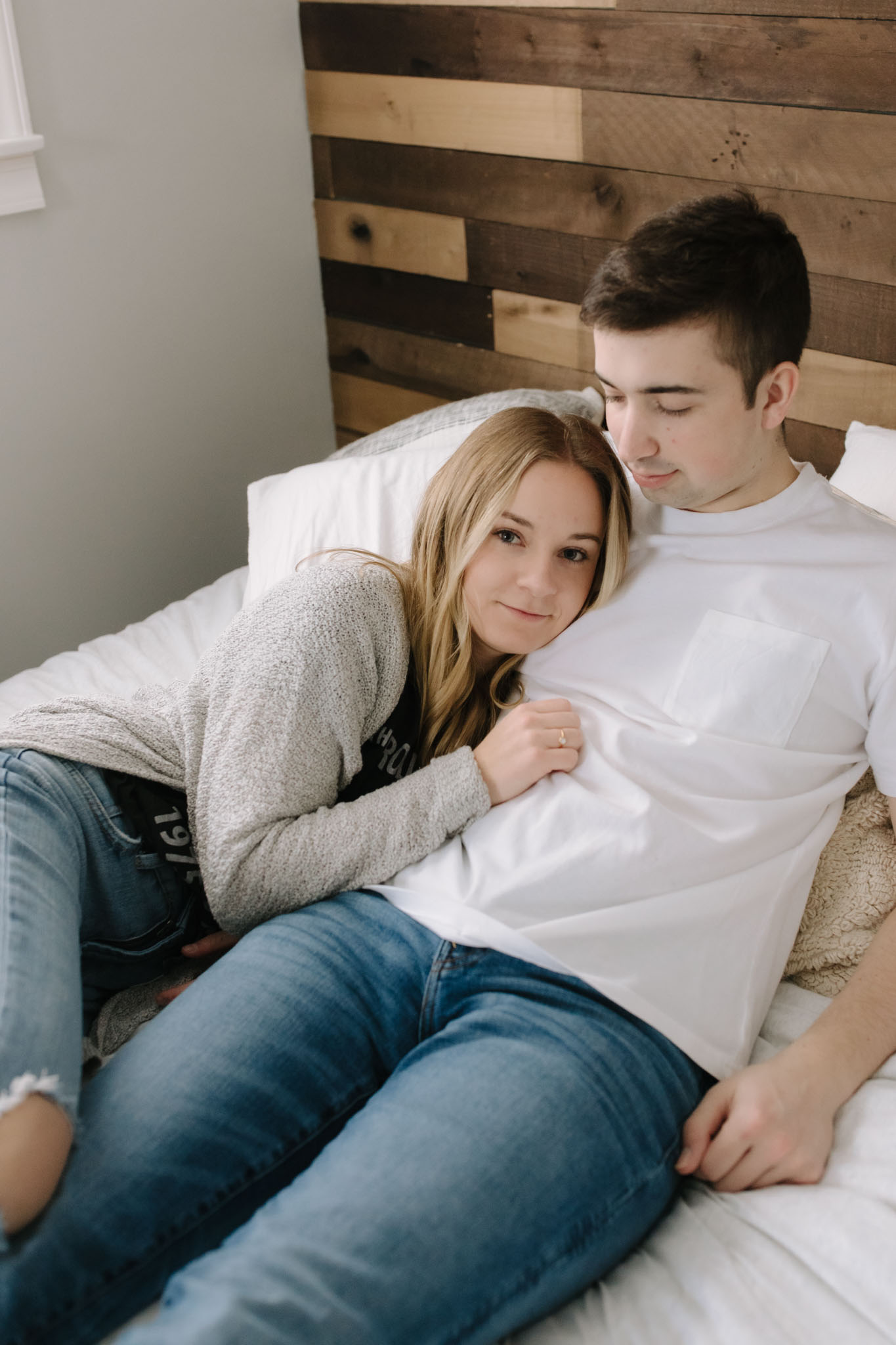Couple cuddled in bed for in-home engagement pictures