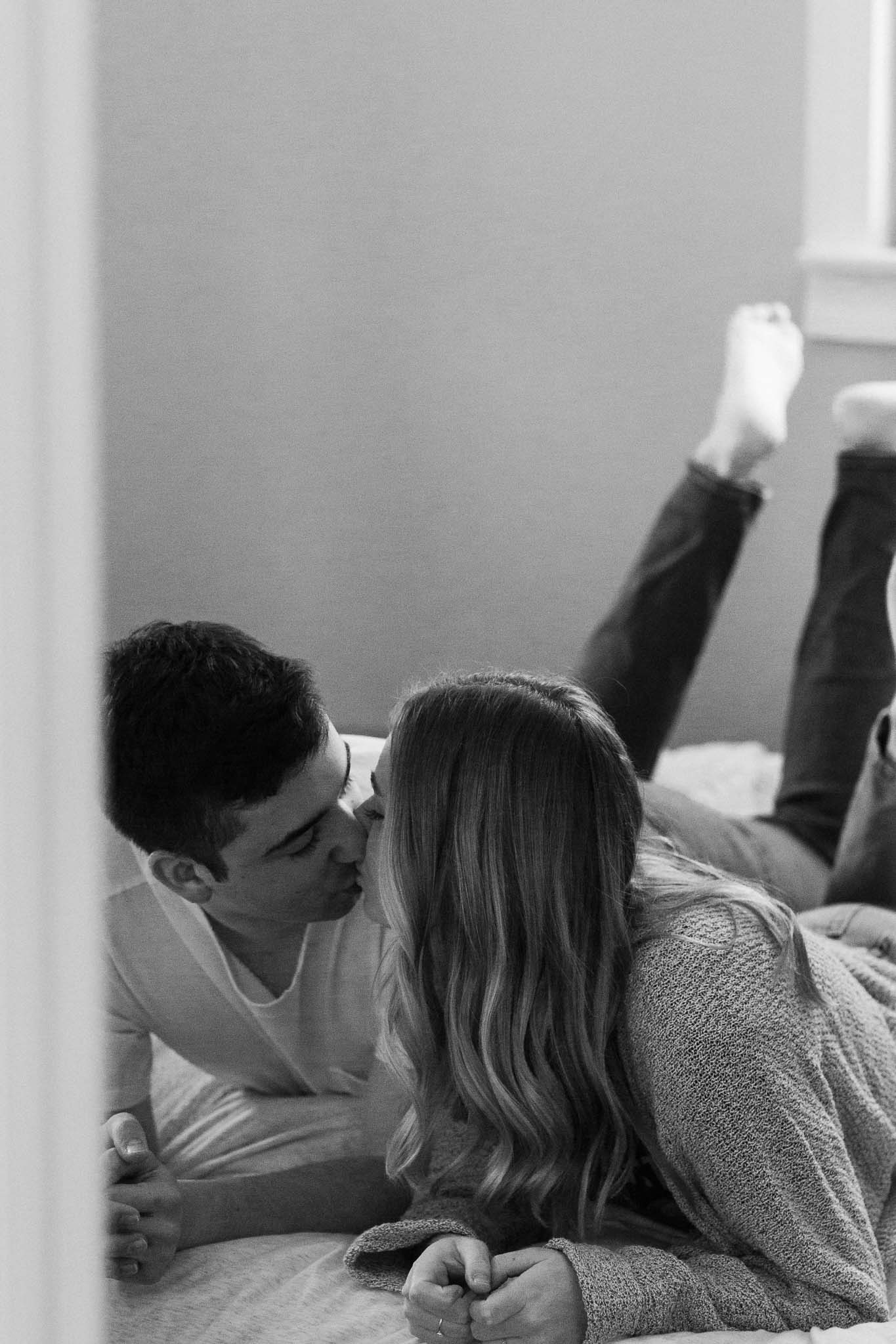 Couple cuddled in bed for in-home engagement pictures