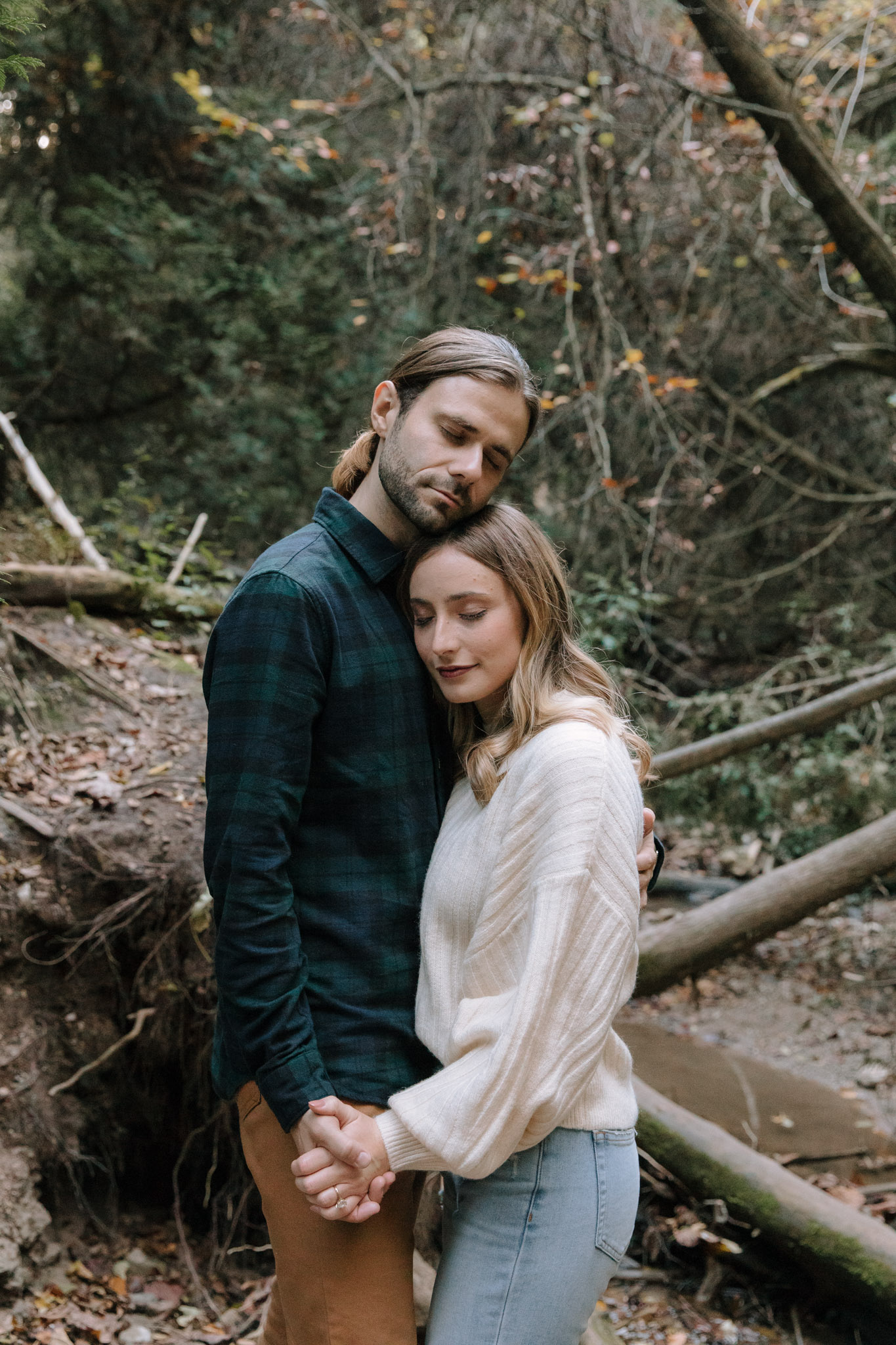 Couple standing chest to chest with their eyes closed, resting their cheeks together during their Wisconsin photos in Port Washington woods