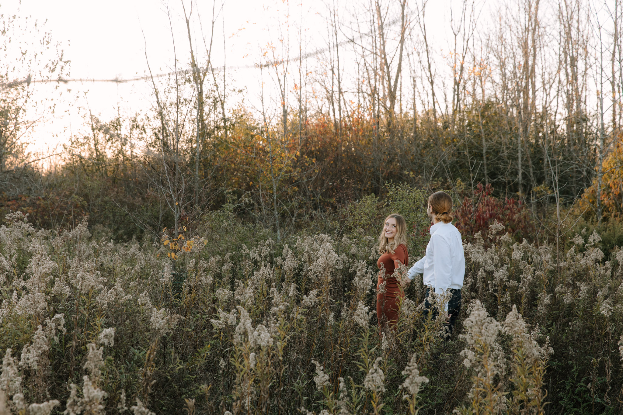 Engagement session with posing based in motion - couple running through a field