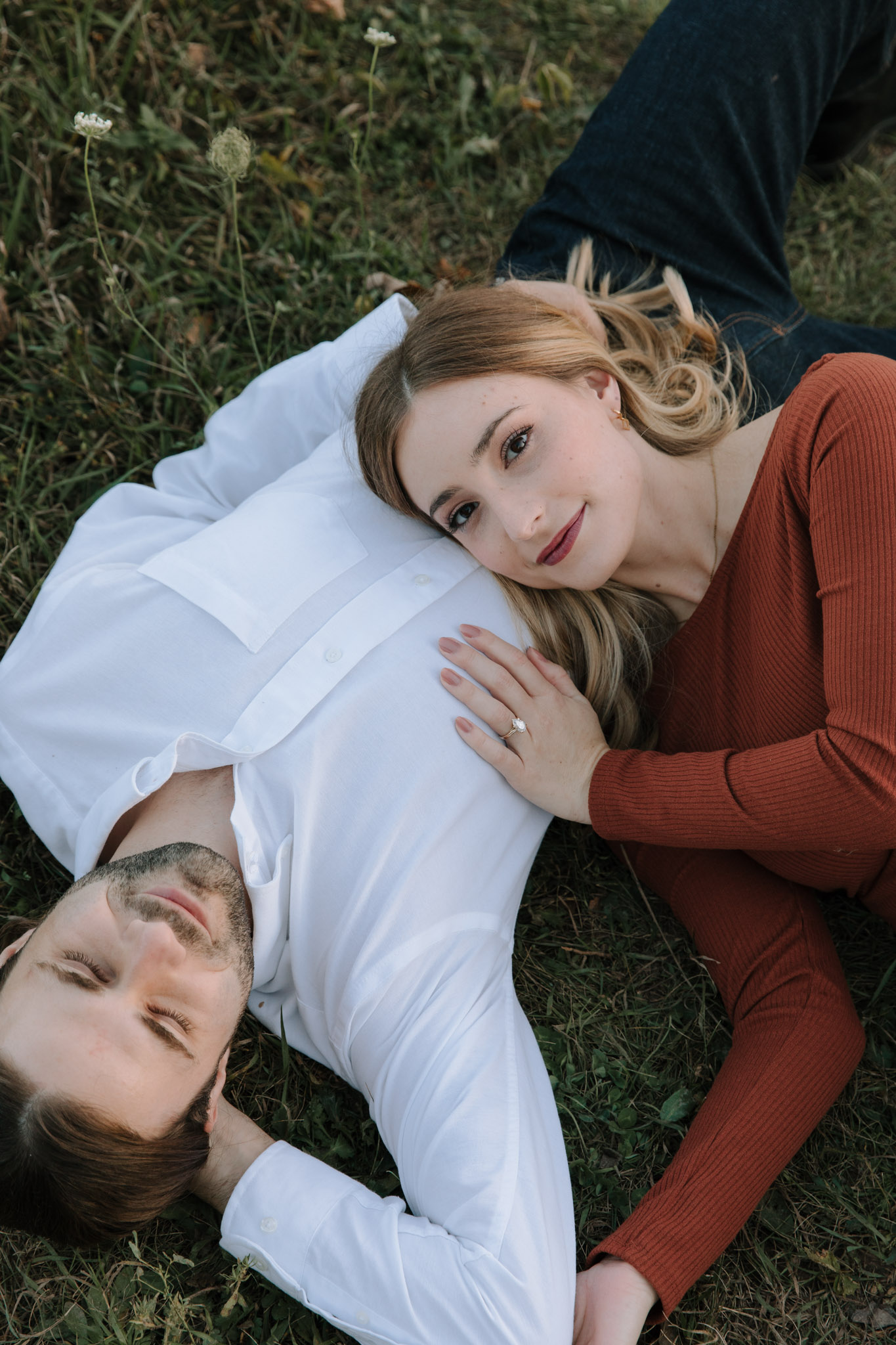2022 Wisconsin Engagement Photographers - couple laying in grass - pear shaped ring - burnt orange dress