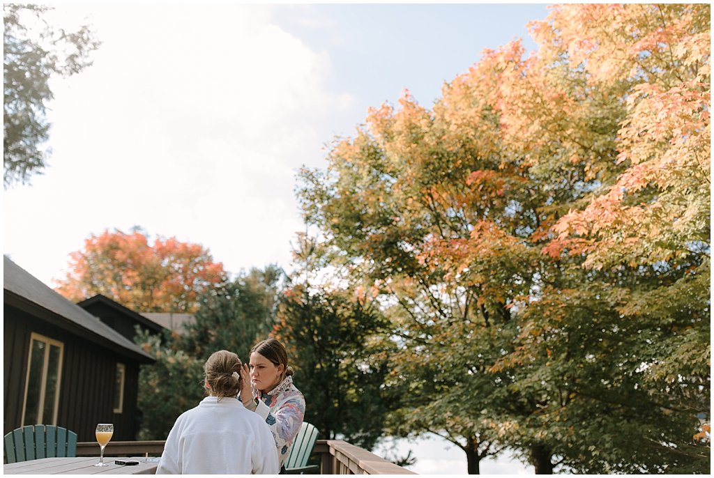 Sister doing bride's makeup with mimosas - unique camp wedding inspiration