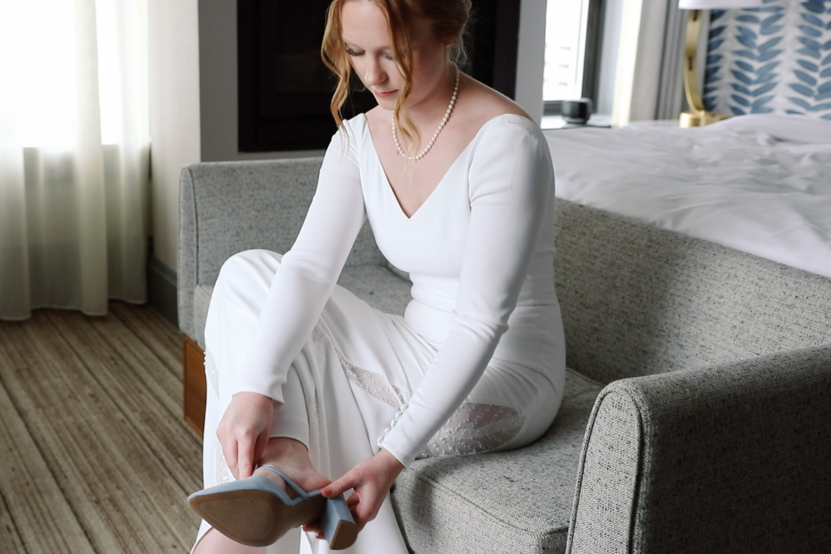 Bride putting on blue wedding shoes at Hotel Northland in Green Bay