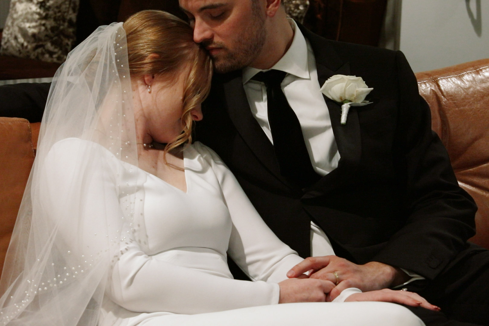 Bride and groom kissing on a leather couch at Hotel Northland