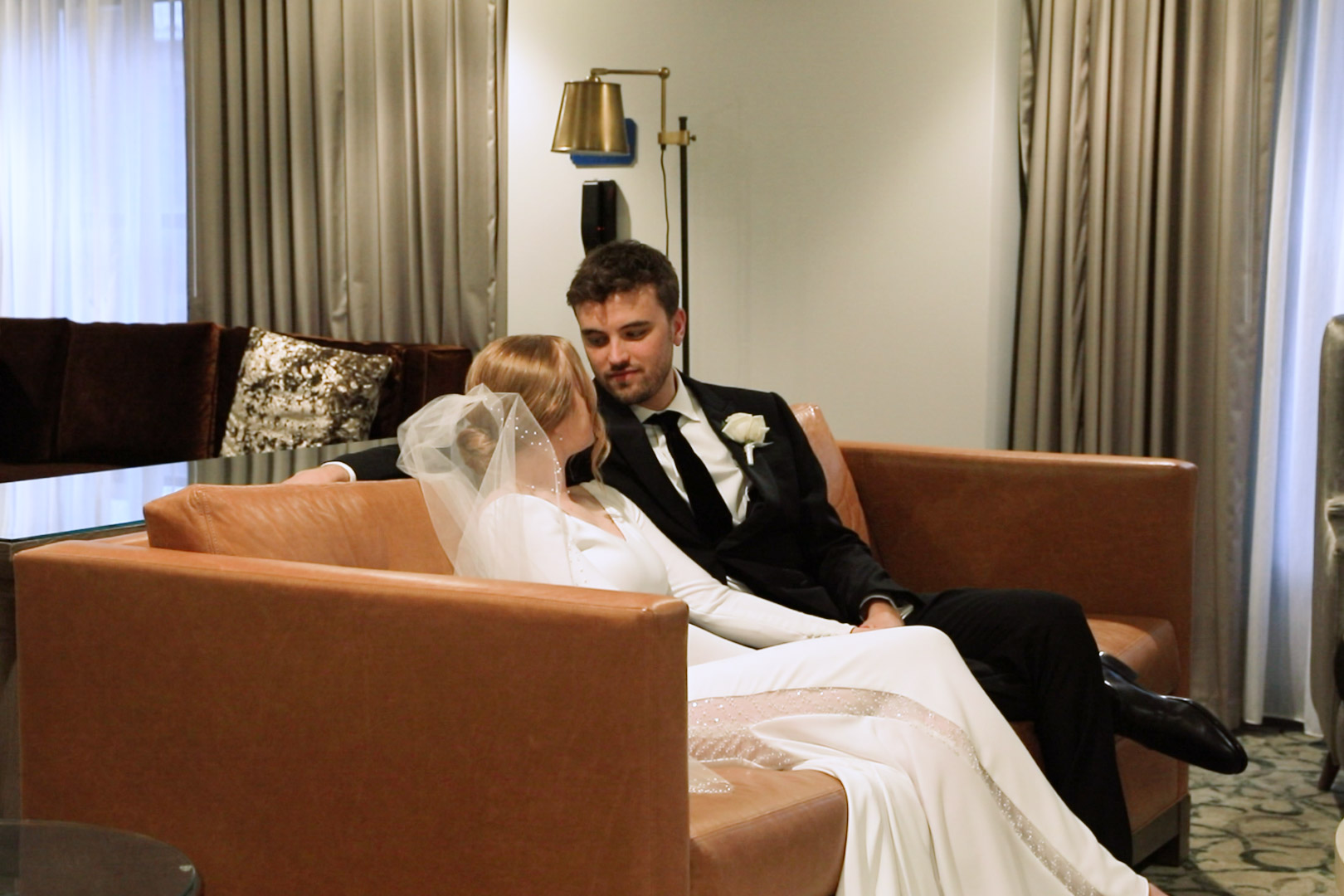 Couple cuddling on the couch in wedding attire
