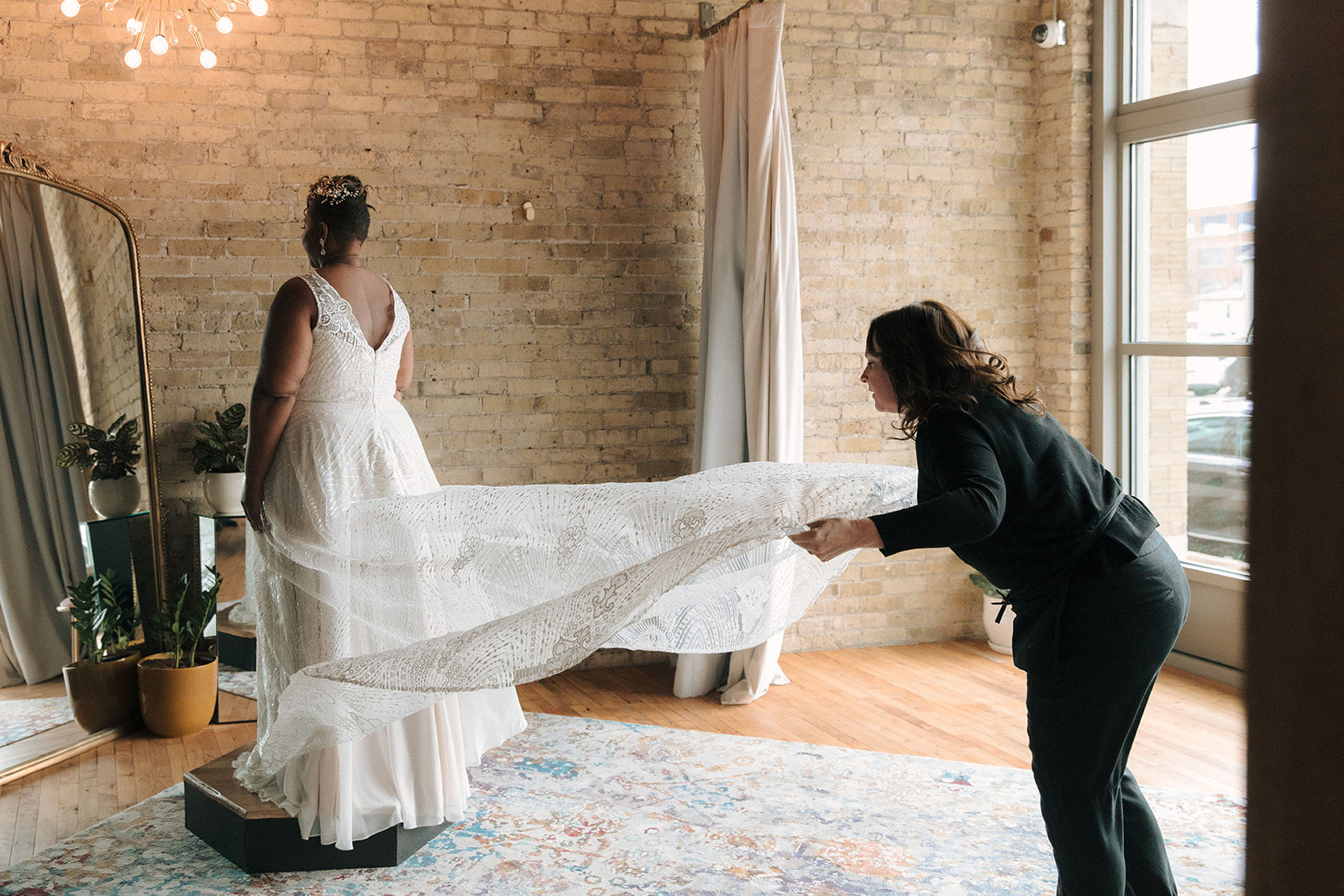 Bridal assistant helping plus size bride into gown - Strike Bridal Bar