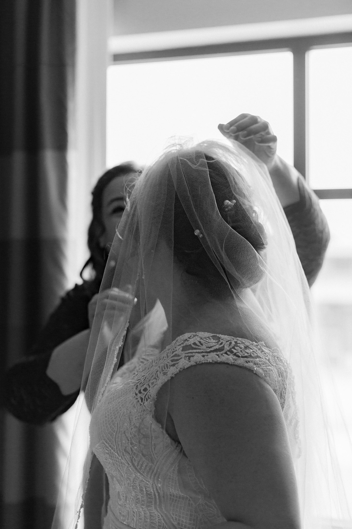 Artistic wedding photo of mother placing homemade veil on bride before St Stanislaus wedding - Hilton Homewood Suites - Wauwatosa