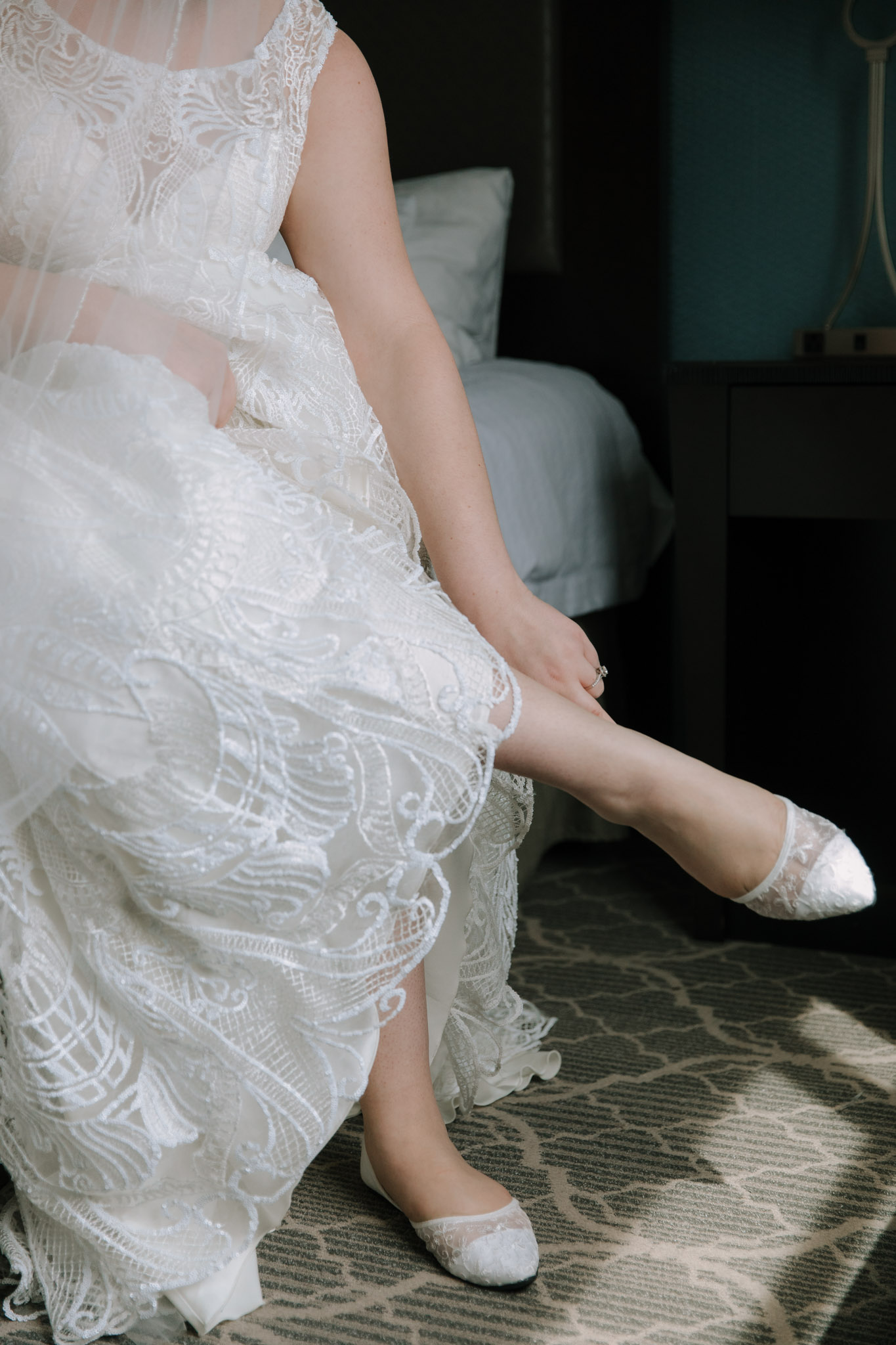 Fine art wedding photo - Bride puting on lace wedding flats before St Stanislaus wedding - Hilton Homewood Suites - Wauwatosa