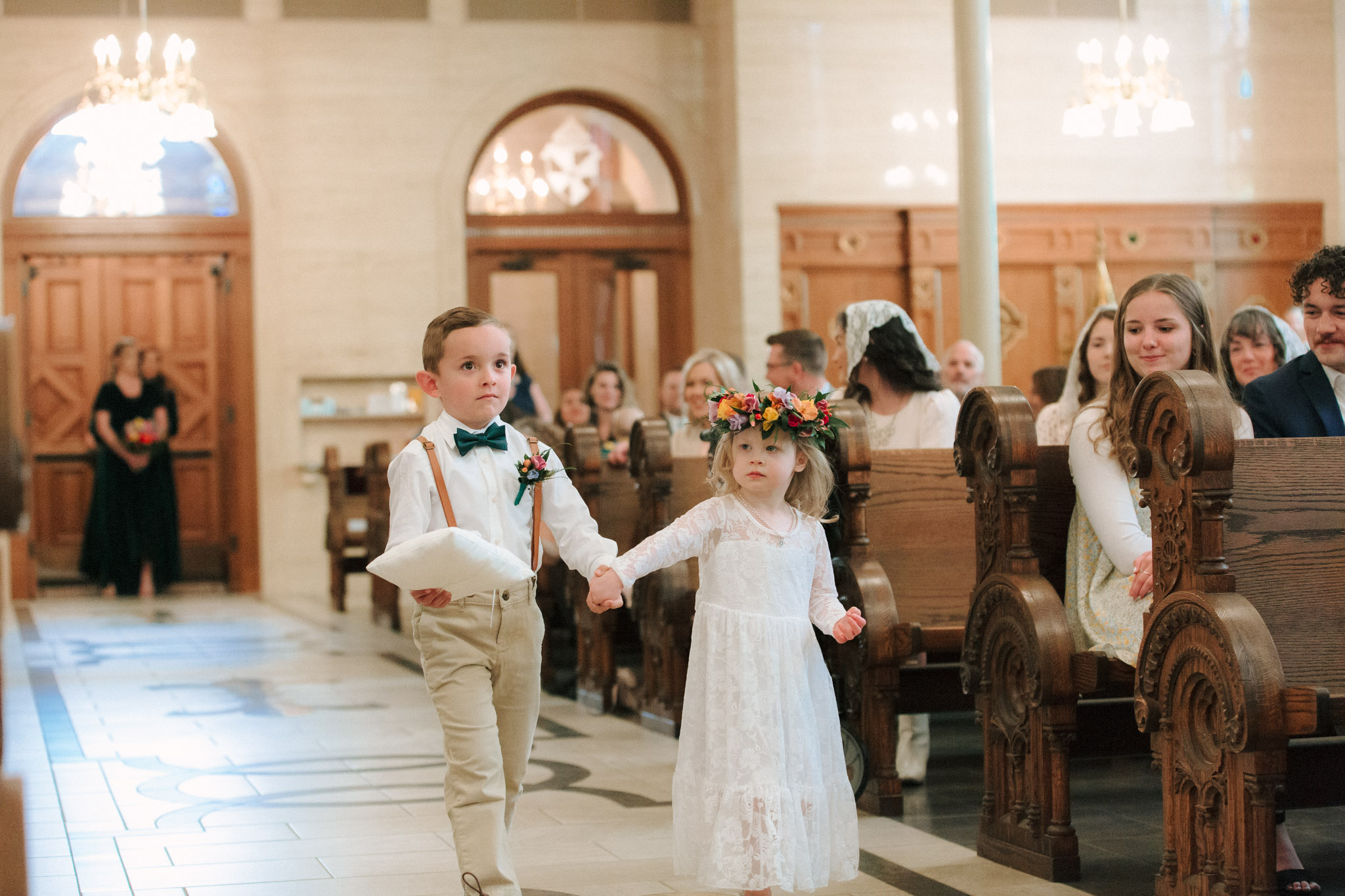 ring bearer and flower girl wearing a brightly colored flower crown walking down the aisle - St Stanislaus wedding
