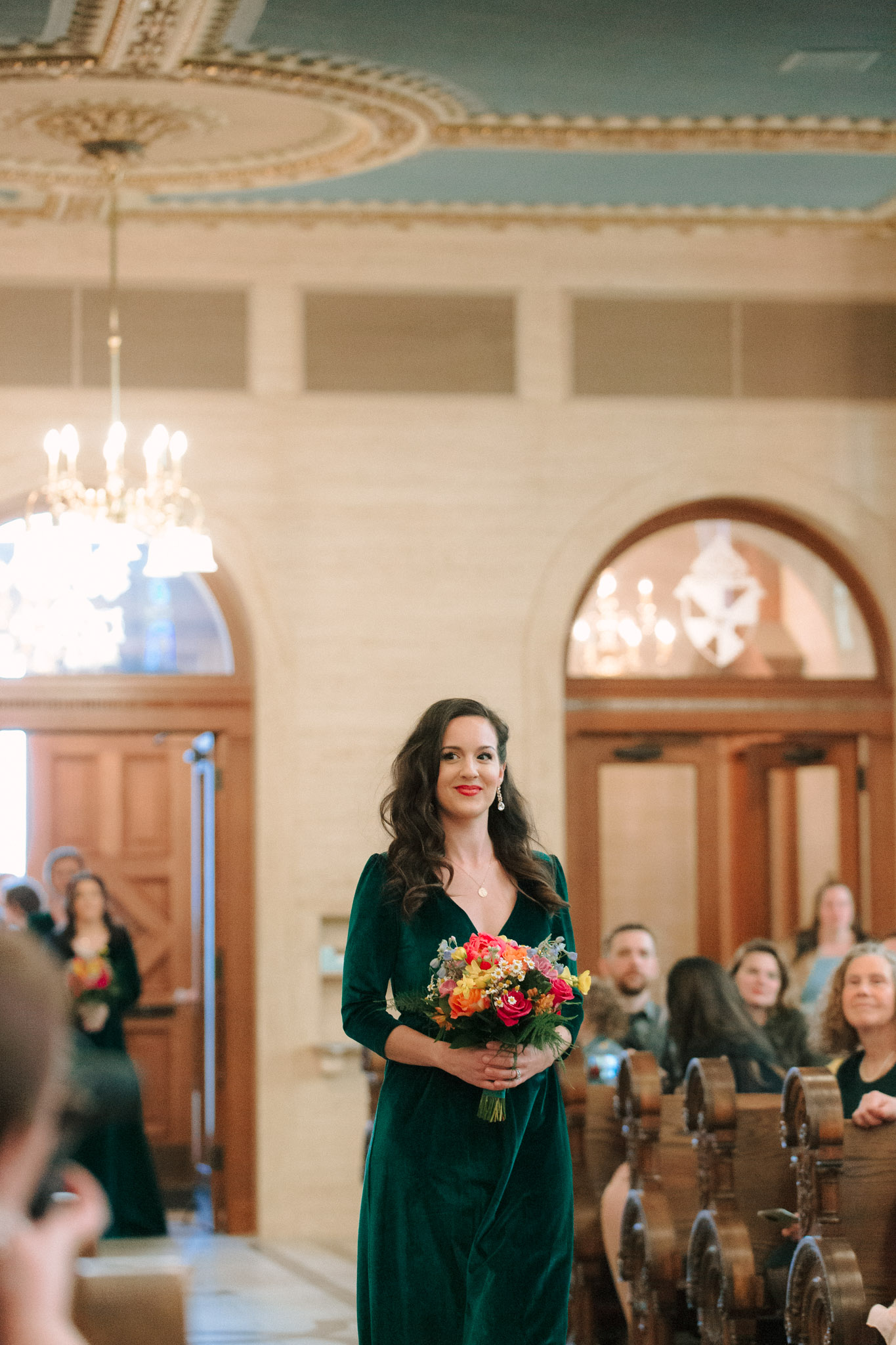 Bridesmaid in green dress and bright colored flowers walking down the aisle - St Stanislaus wedding