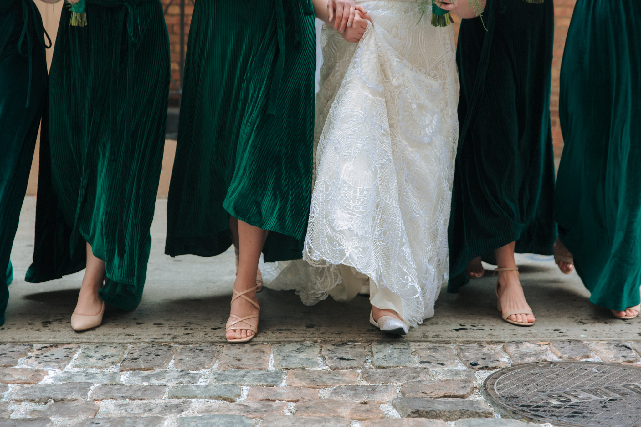 Bridesmaids walking in emerald dresses outside of Pabst Theatre for wedding pictures