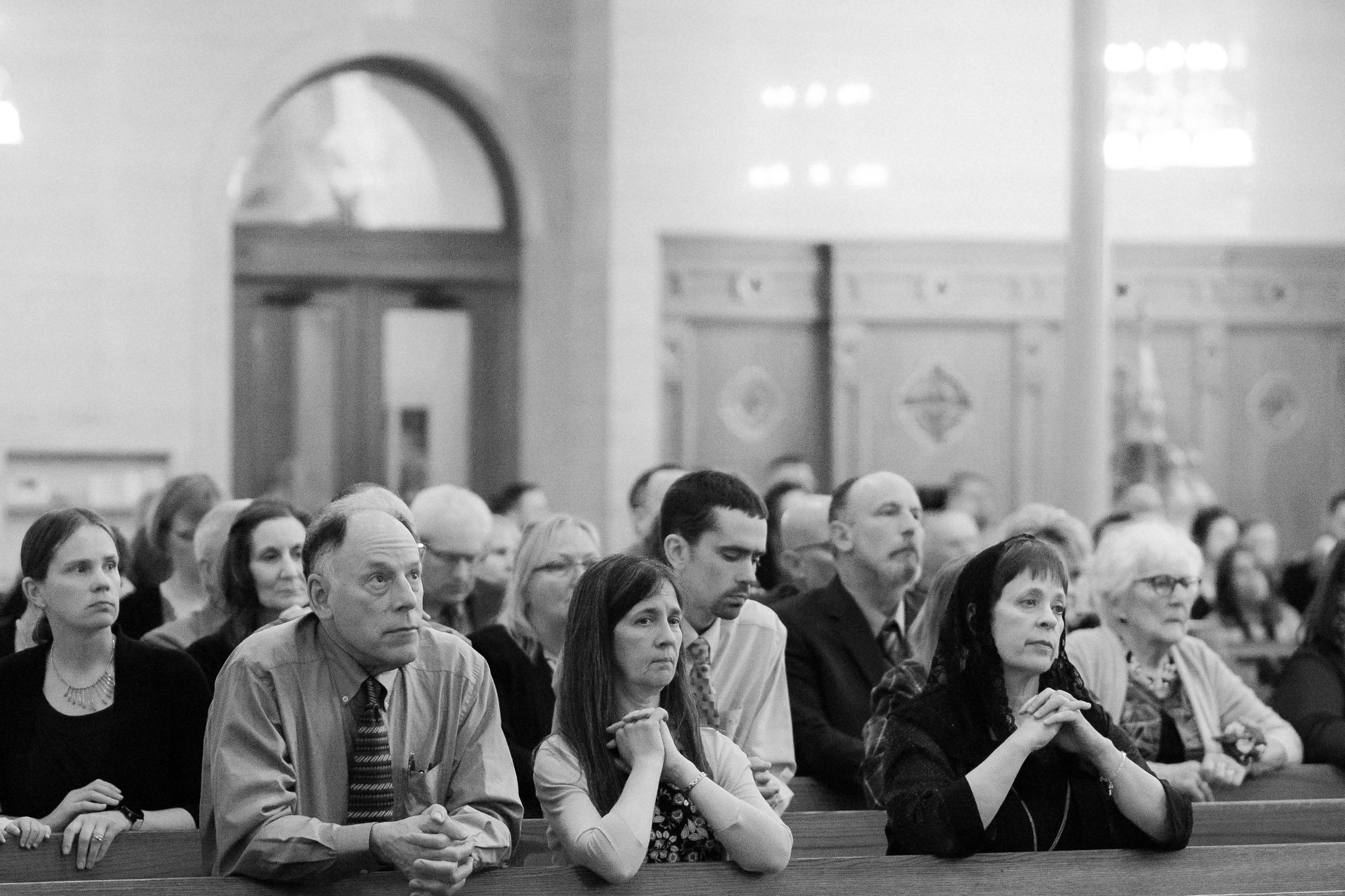 Black and white photo of guests sitting and praying - St Stanislaus wedding