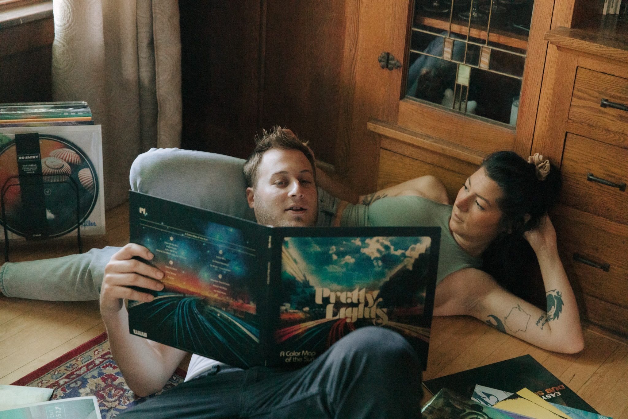 Retro 1960s inspired engagement photos with a blunt, record player, and guitar. Couple laying on the floor looking at a pretty lights record