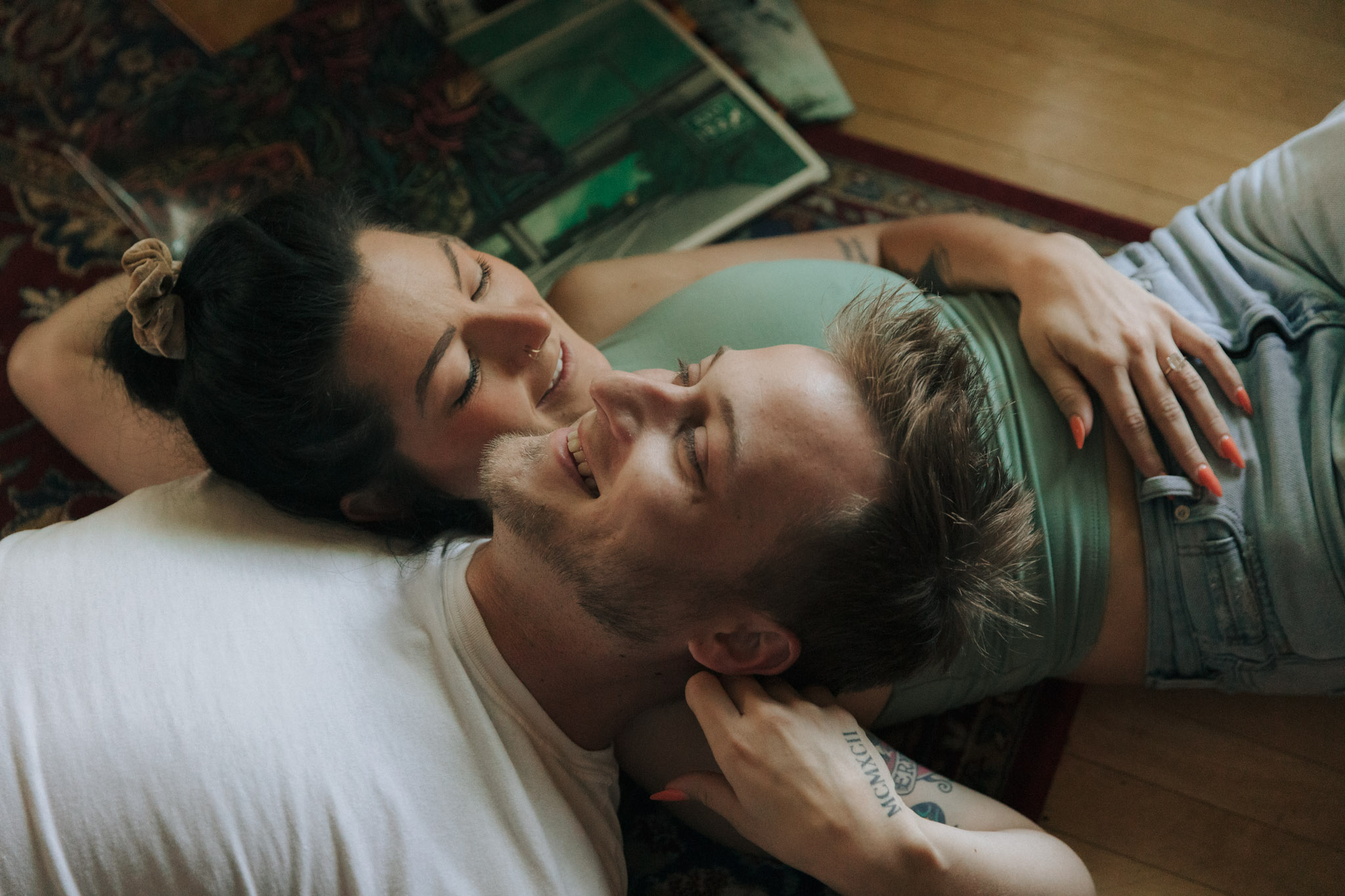 A couple laying on a vintage rug with a guitar and records on the floor