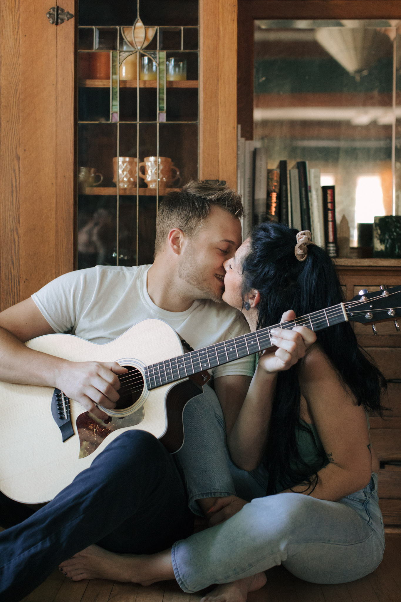 Couple kissing in their retro Milwaukee house while playing guitar