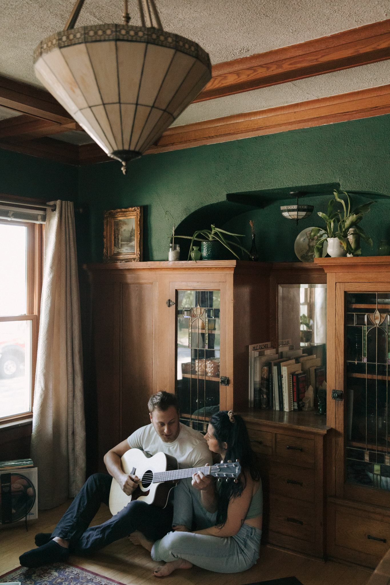 A couple in a vintage craftsman Milwaukee home playing guitar on the floor