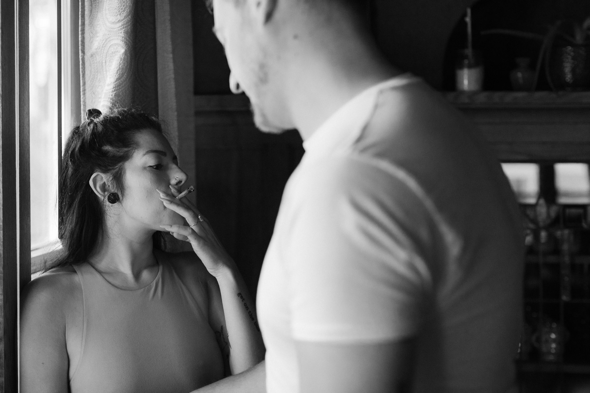 Moody black and white image of a girl smoking in a vintage home