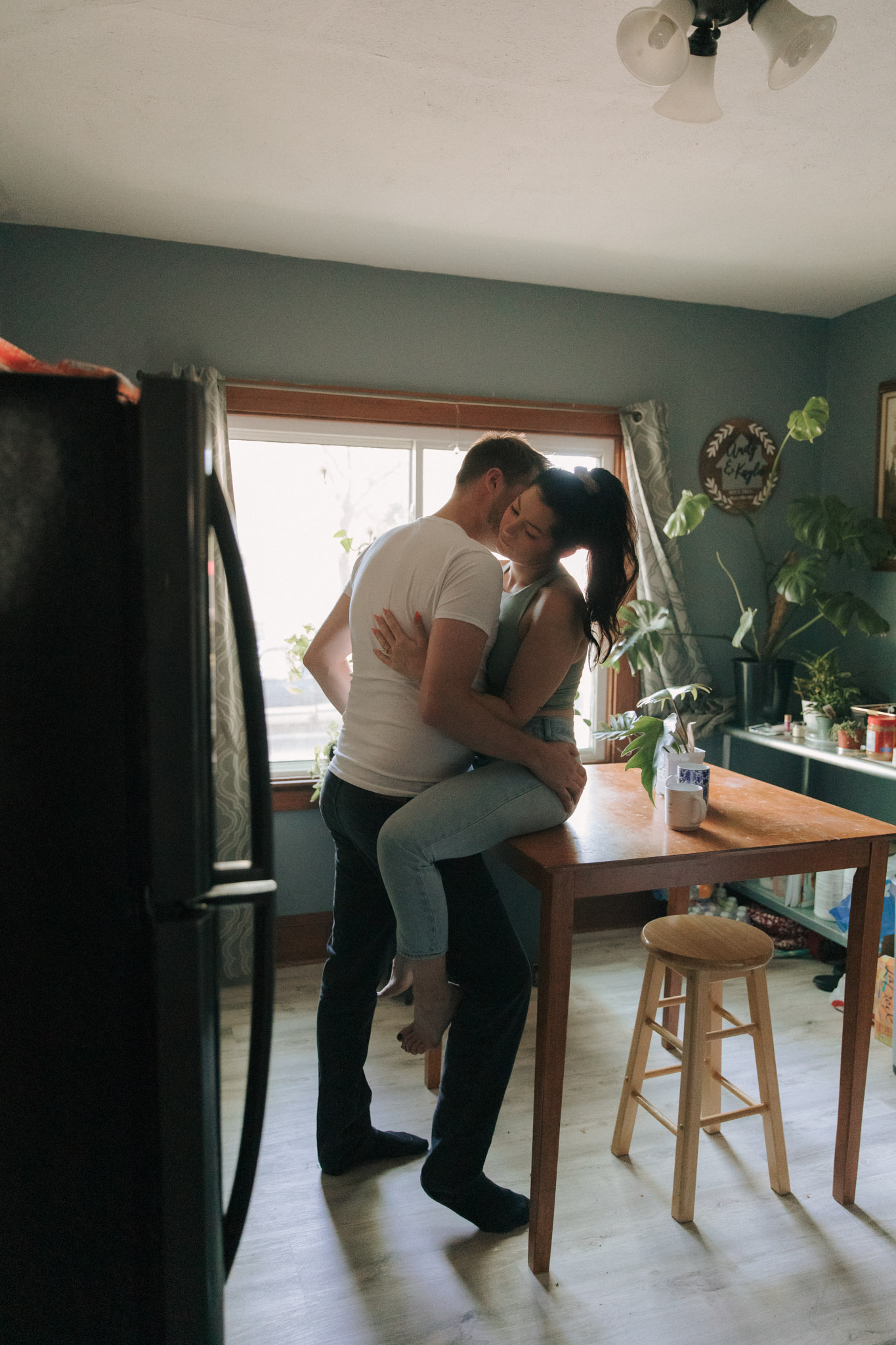 A man kissing a woman who is sitting on a kitchen counter