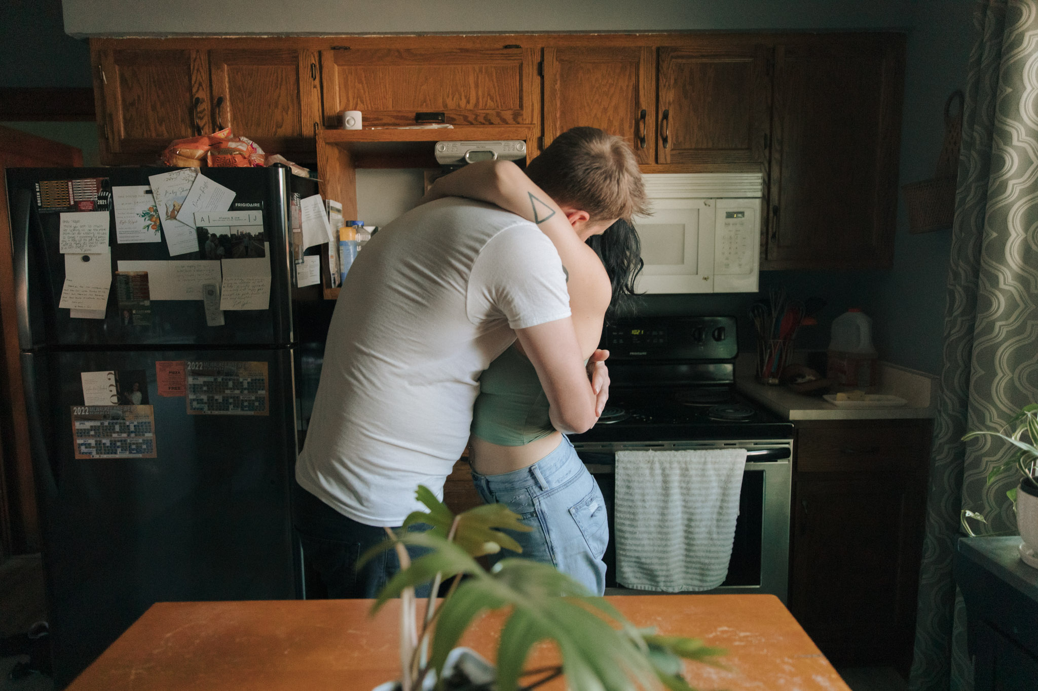Milwaukee engagement photographers Kayla Hurst of Emerald Tide Photography hugging her fiance in the kitchen