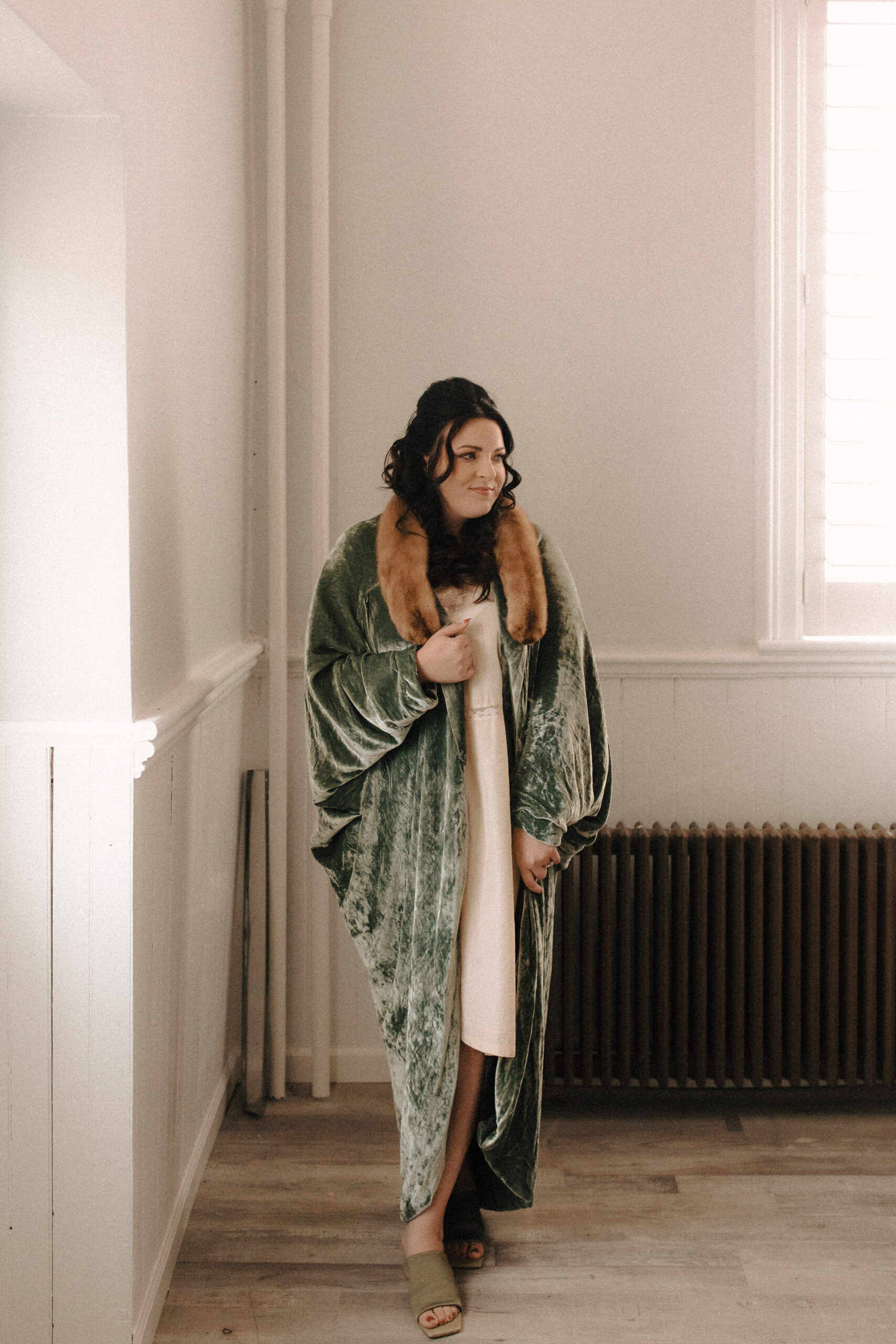 Bride with Priscilla Presley inspired retro hair and makeup wearing a green velvet robe with a fur collar and european vintage nightgown
