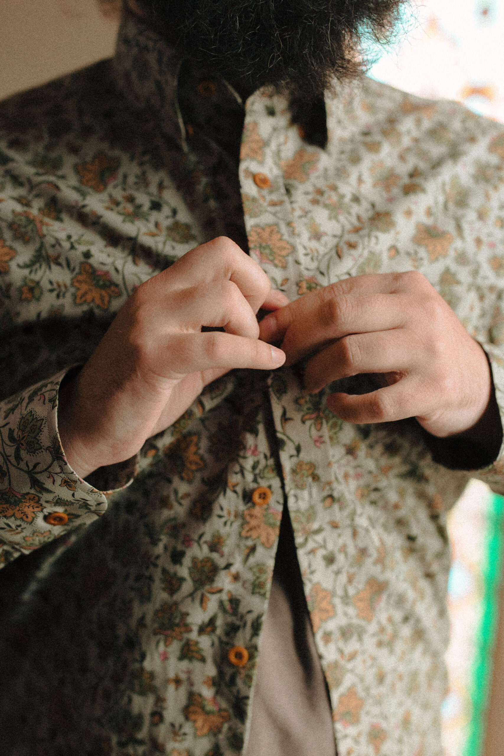 closeup photo of groom buttoning his retro wedding shirt