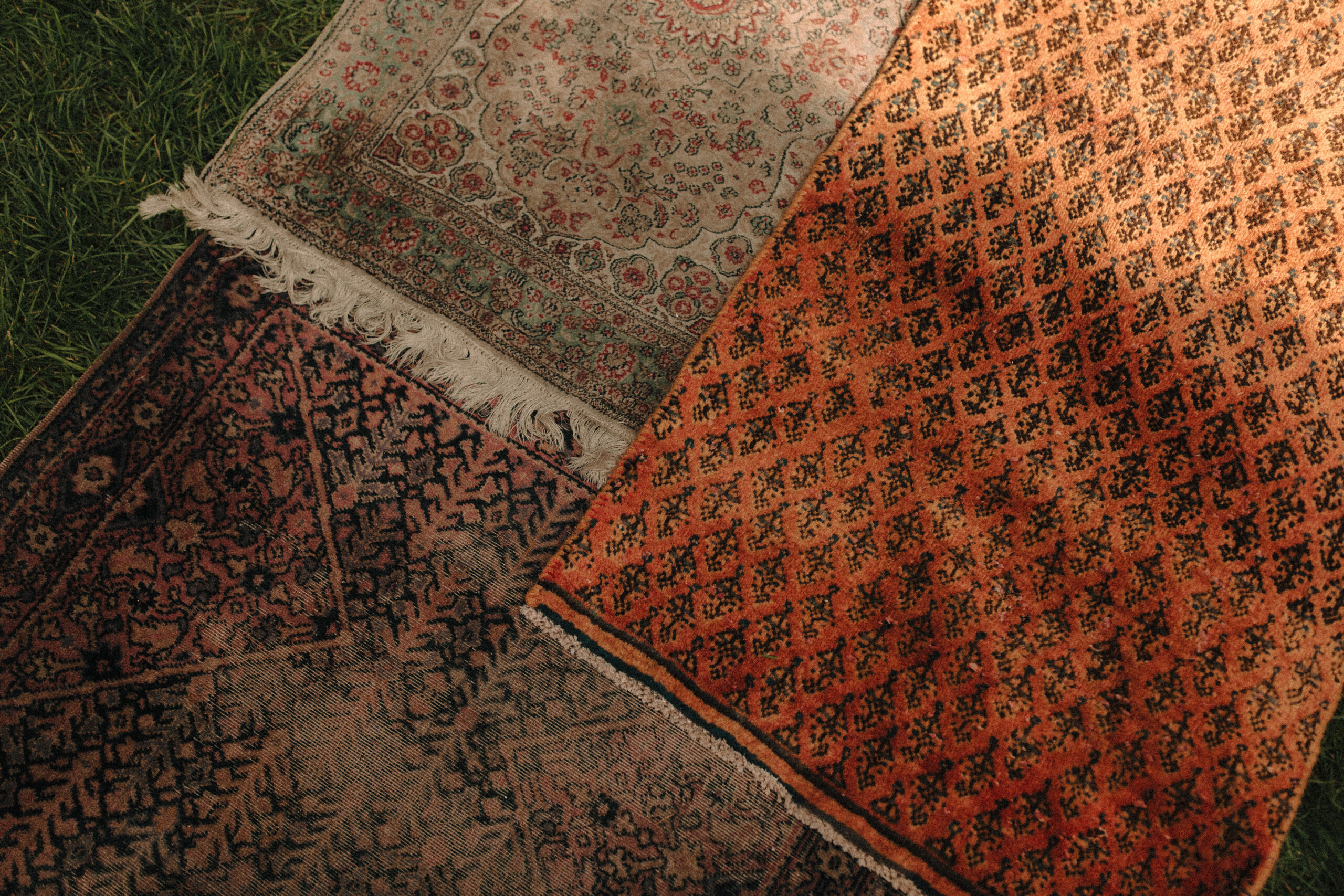 A pile of orange, red, pink, and brown rust-toned rugs being used as a wedding aisle runner
