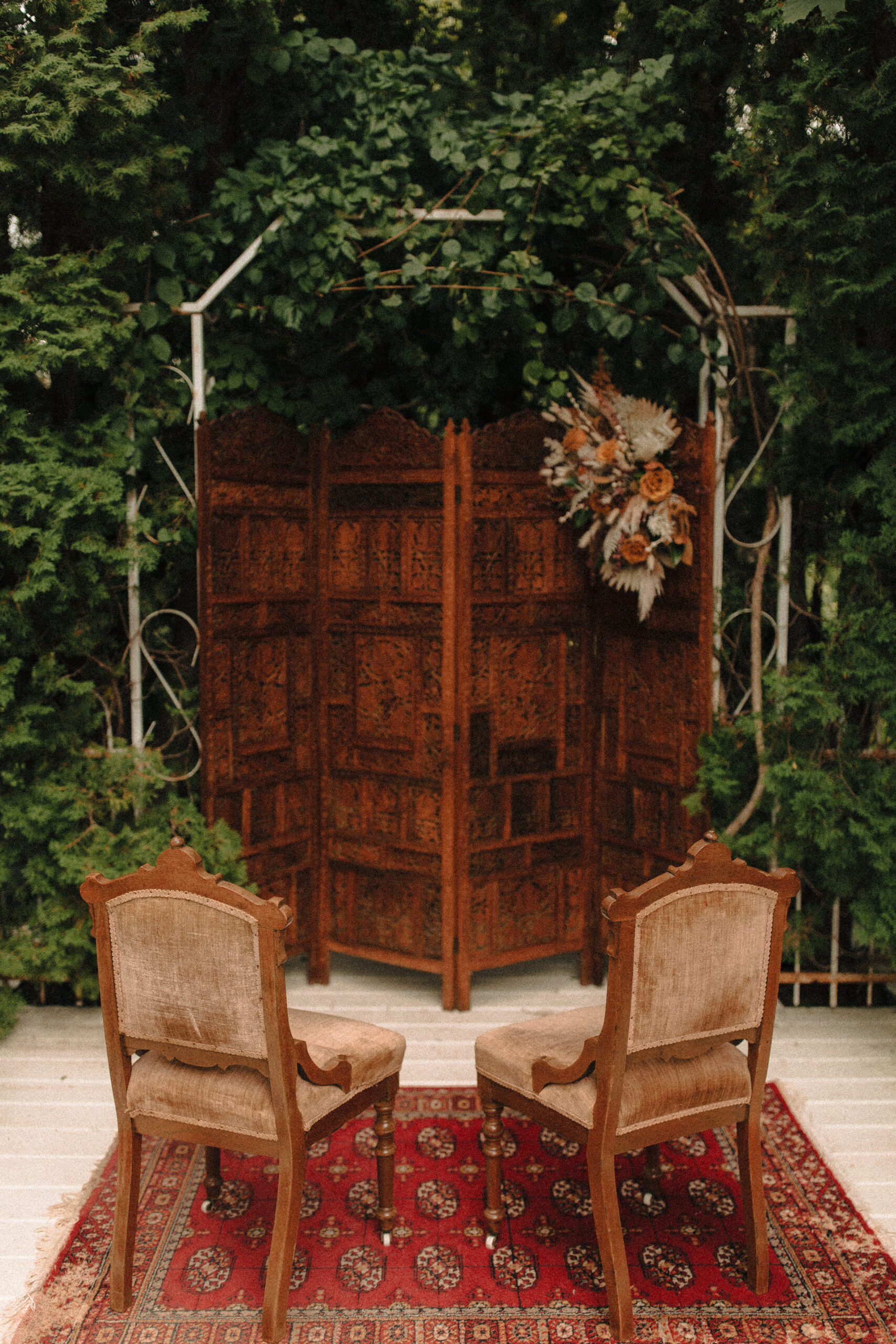 victorian revival romantic wedding ceremony altar with boho flowers and upholstered chairs