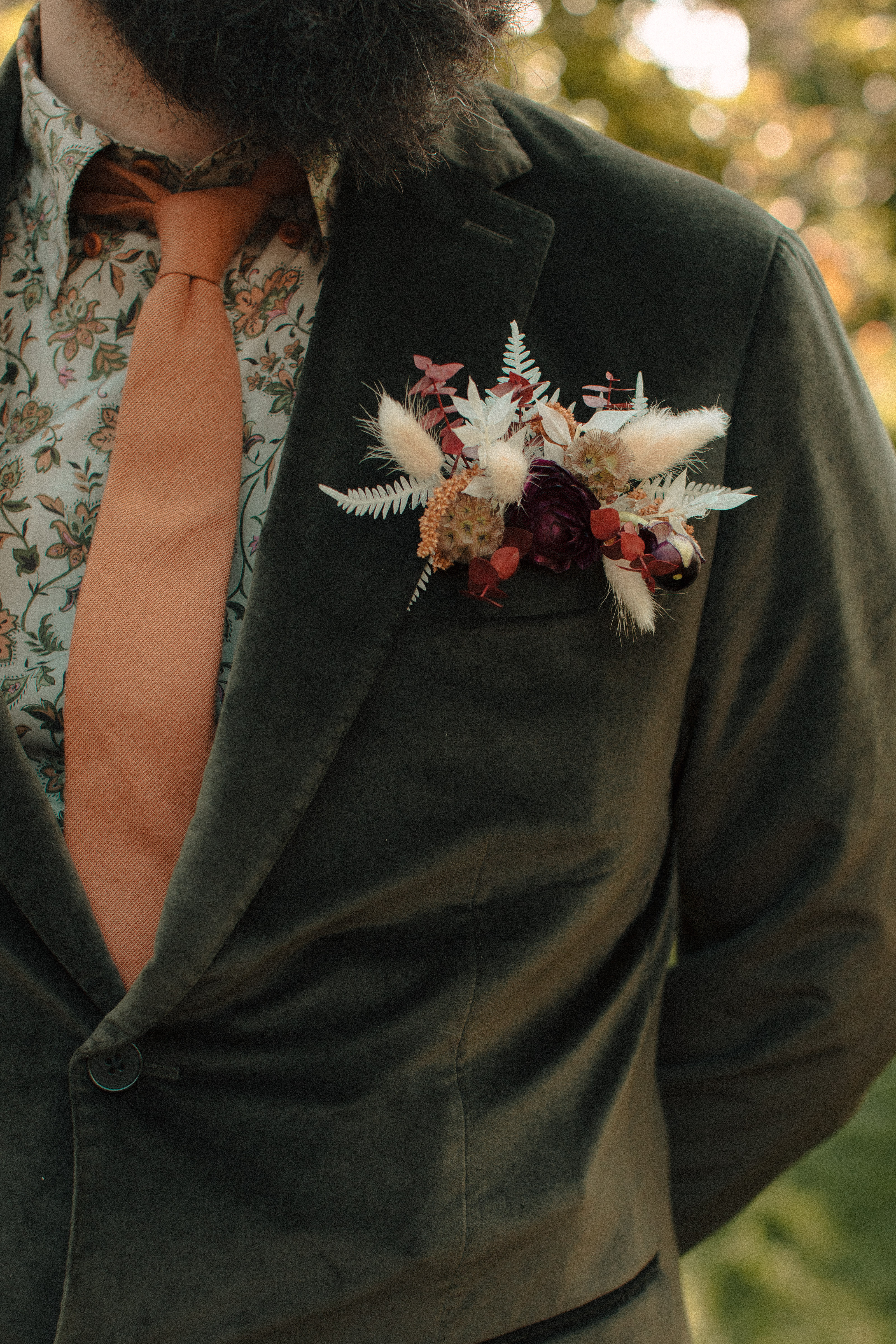 Groom's flower arrangement pocket square for suitcoat tucked into a green velvet jacket