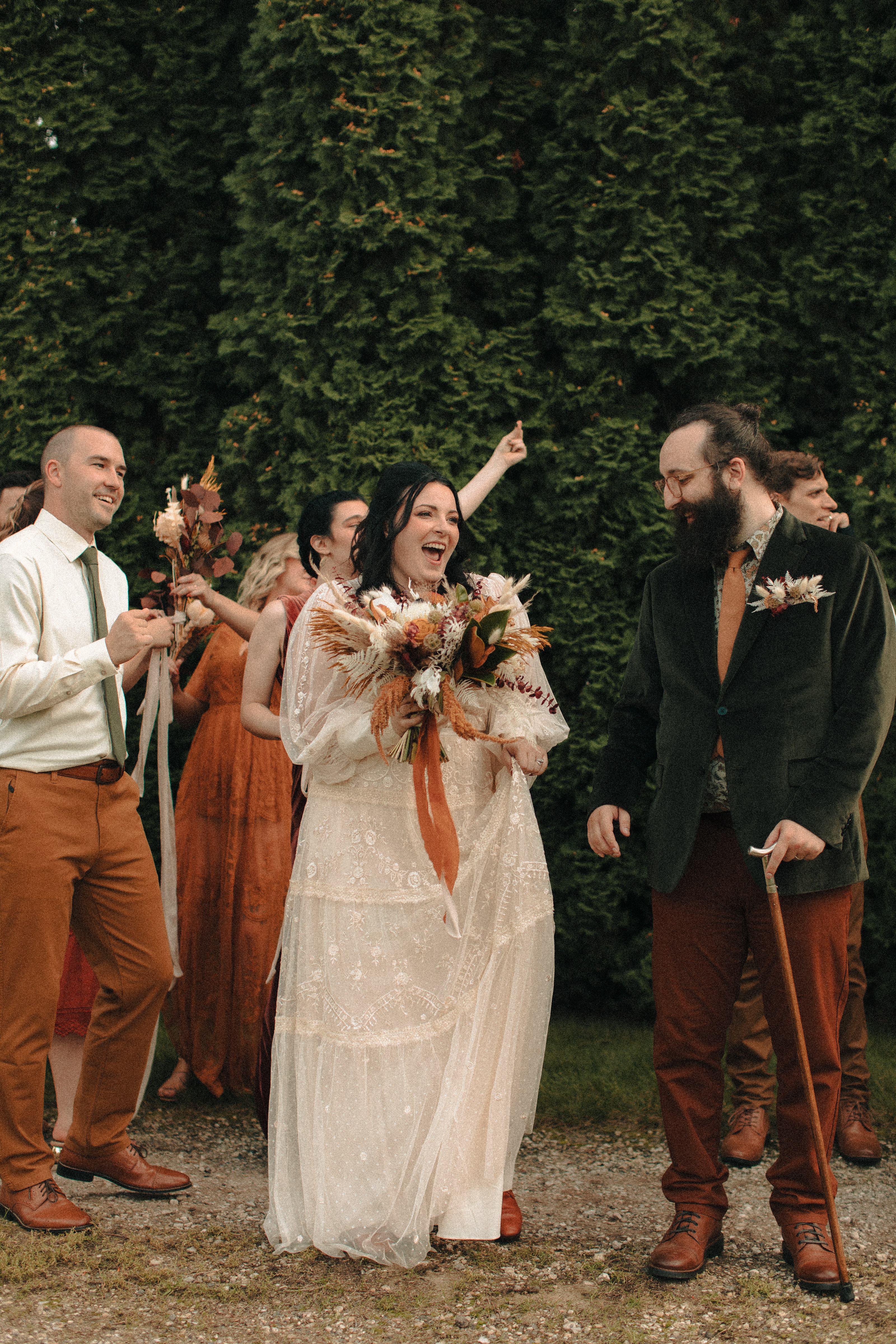 Wedding party wearing creams, golds, oranges, and reds with green accents