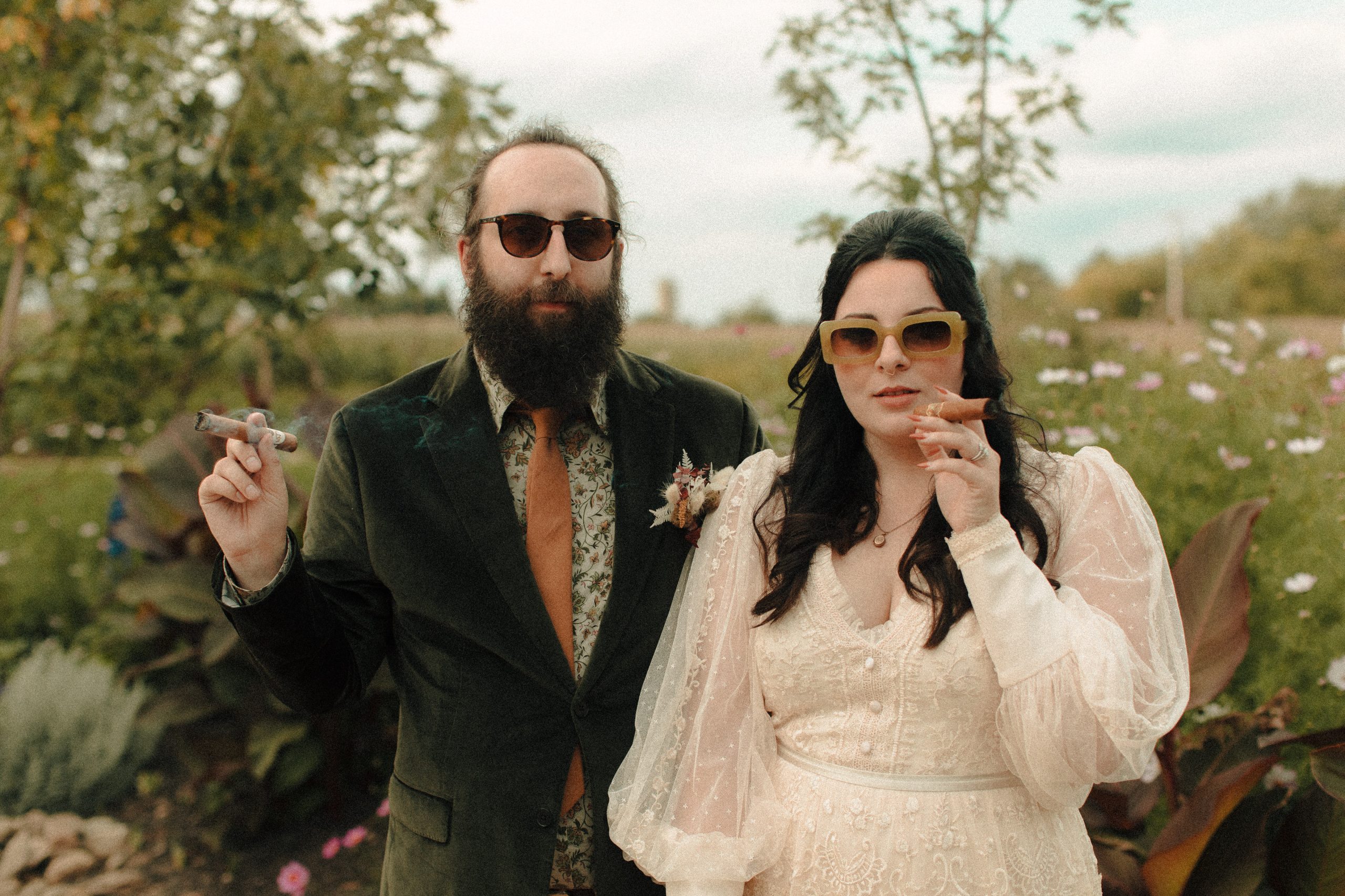 Couple smoking at Speakeasy inspired cigar bar at a wedding with vintage lighters. Bride is wearing vintage green sunglassess